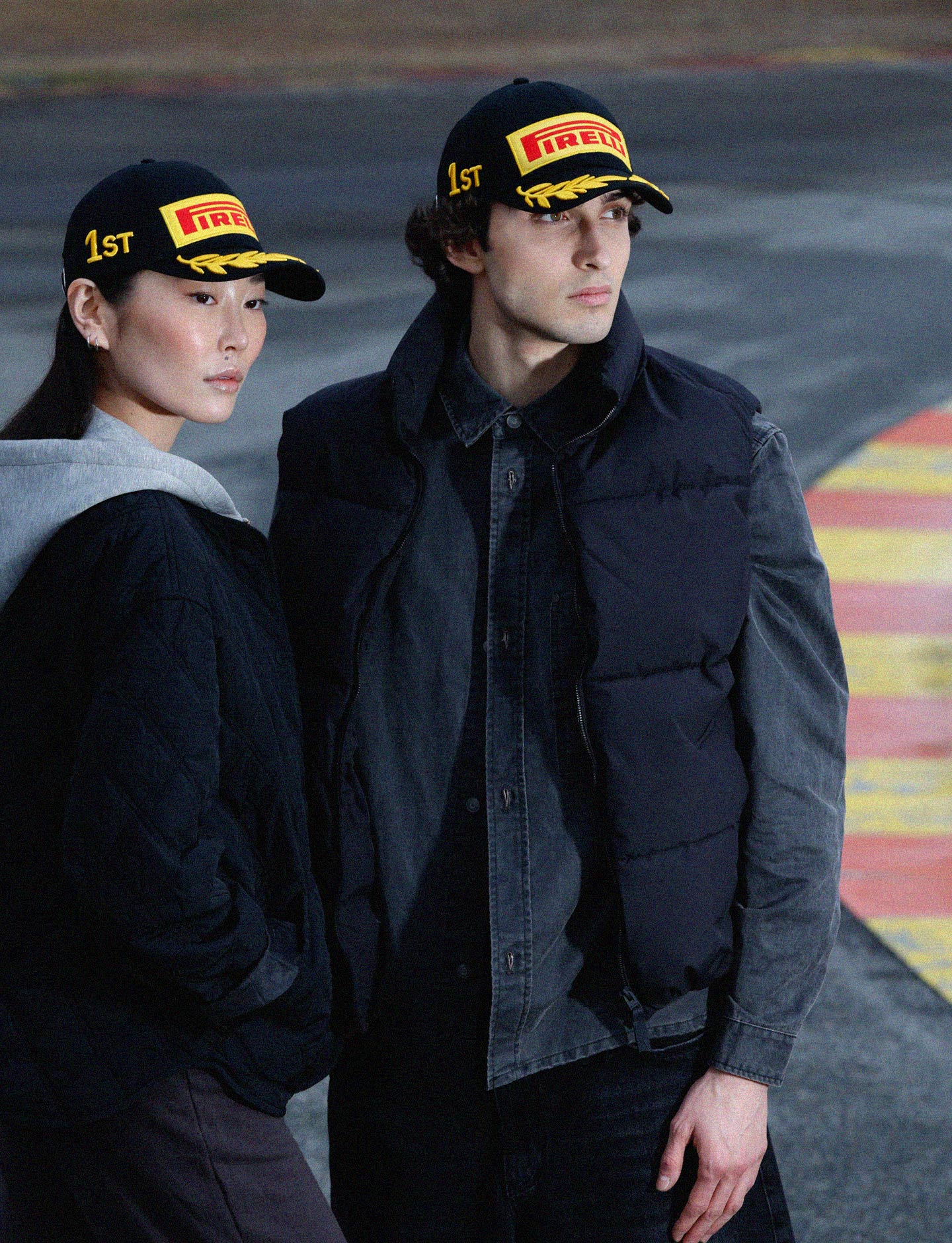 Two people wearing Pirelli hats on a track background