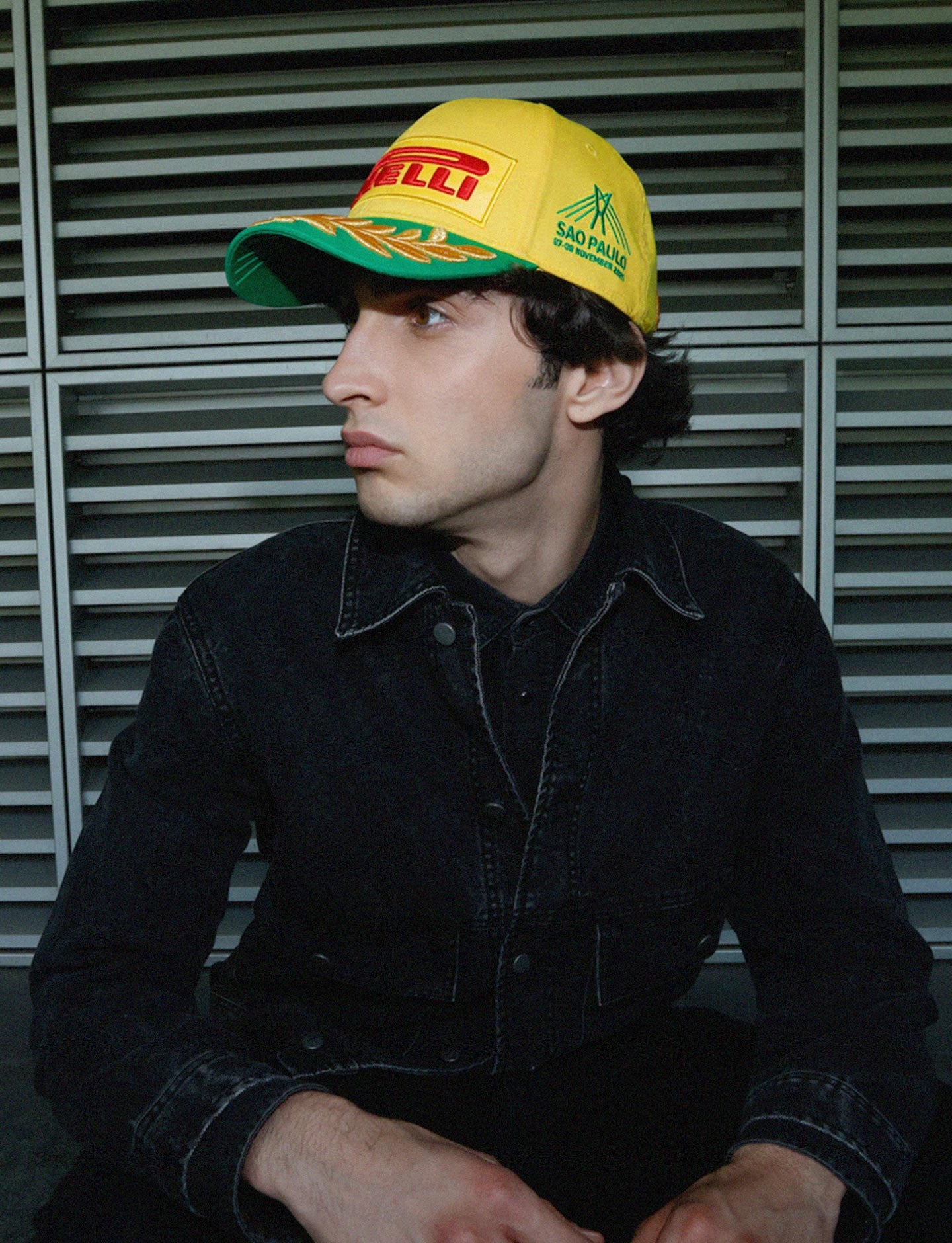 Person wearing a yellow cap with branding against a metallic background