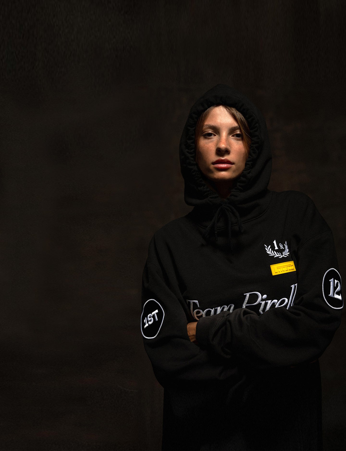 Person wearing a black Team Pirelli hoodie with logos on a dark background