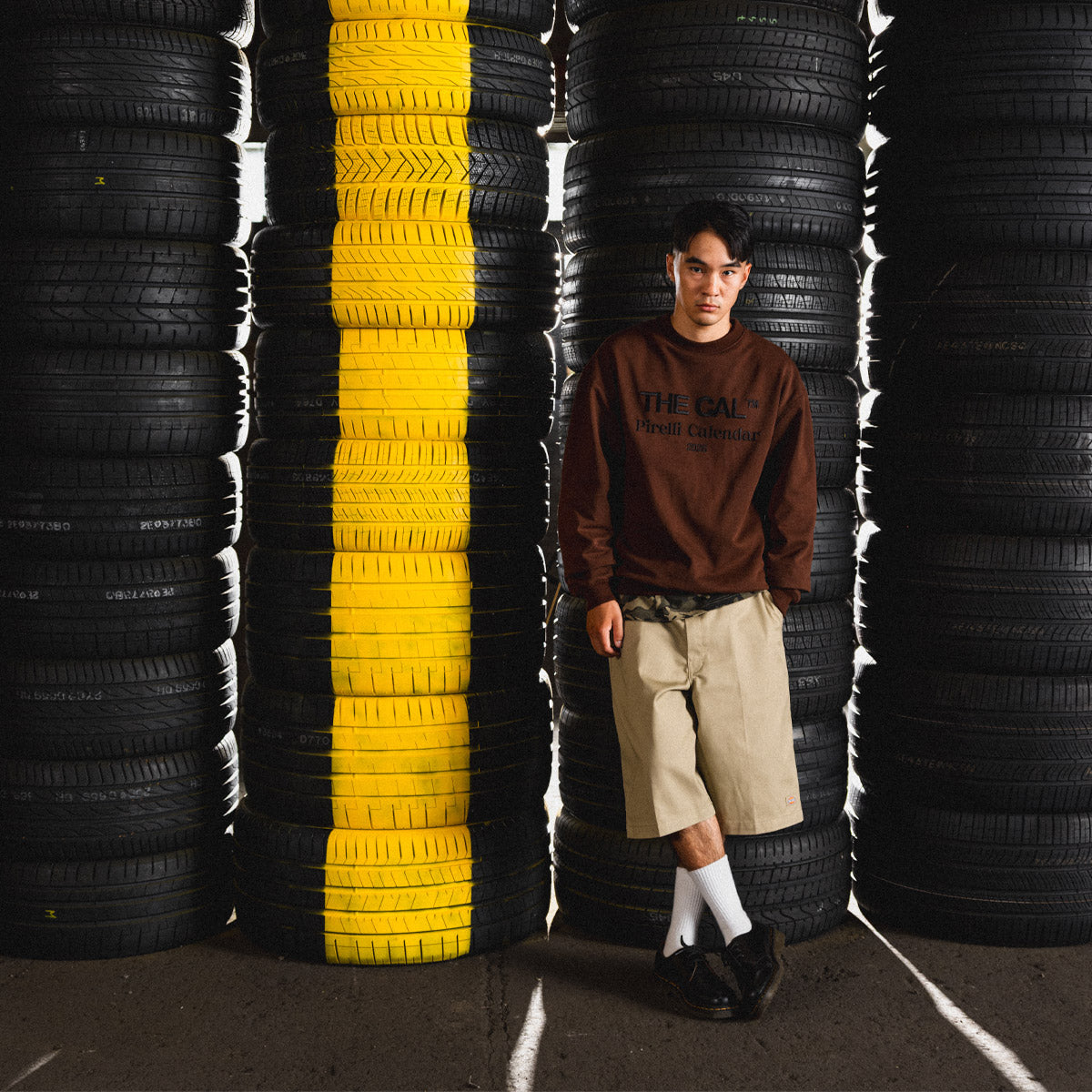 Person standing between stacks of tires with a yellow stripe