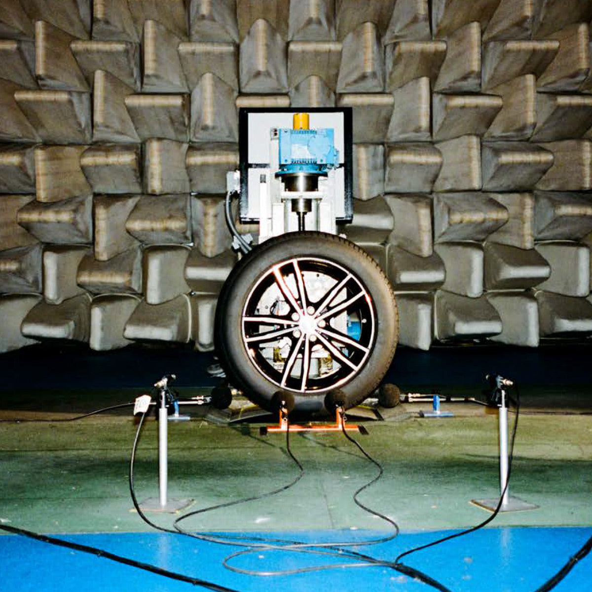 Tire being tested in a anechoic chamber with acoustic foam panels.