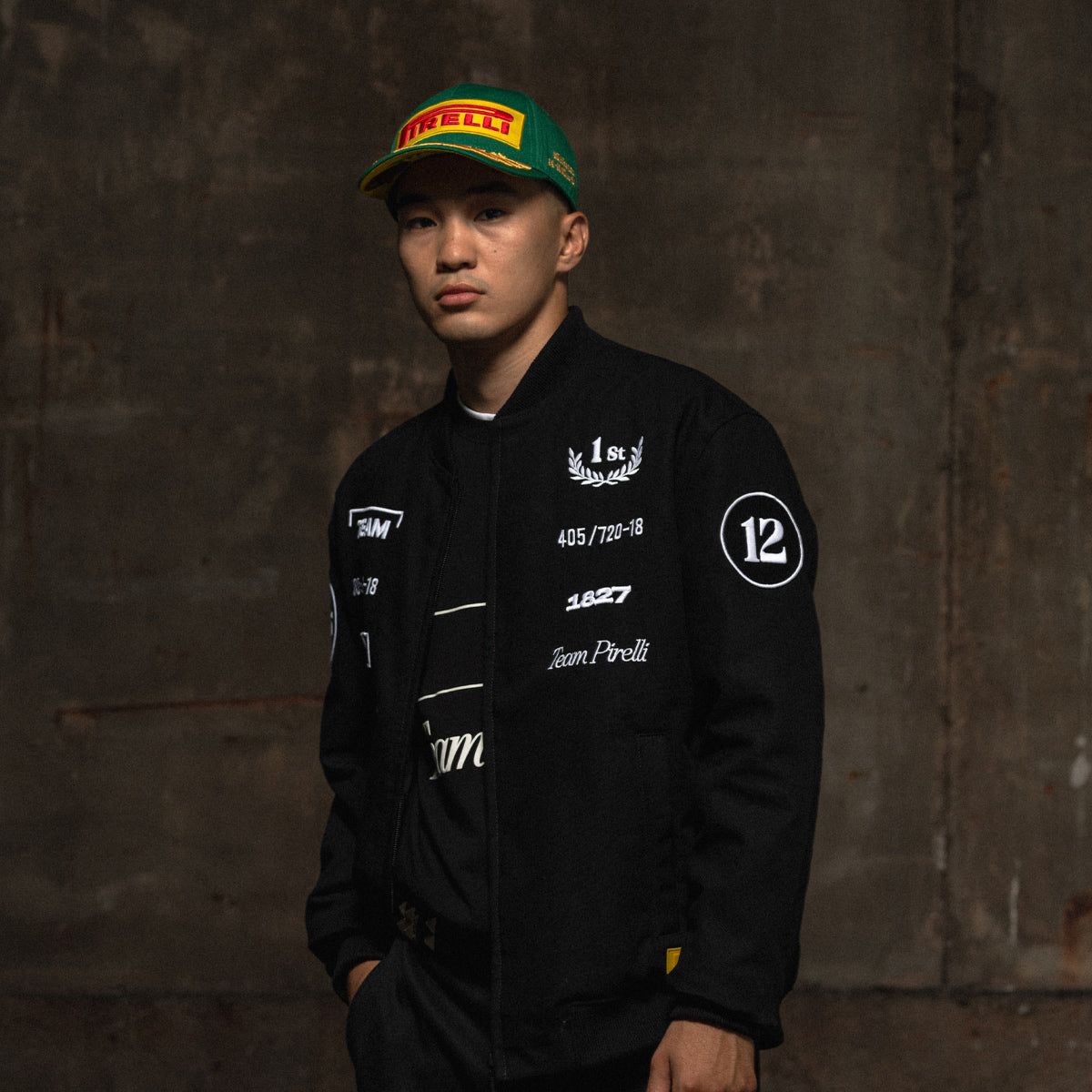 Person wearing a black Pirelli racing jacket with logos against a dark background