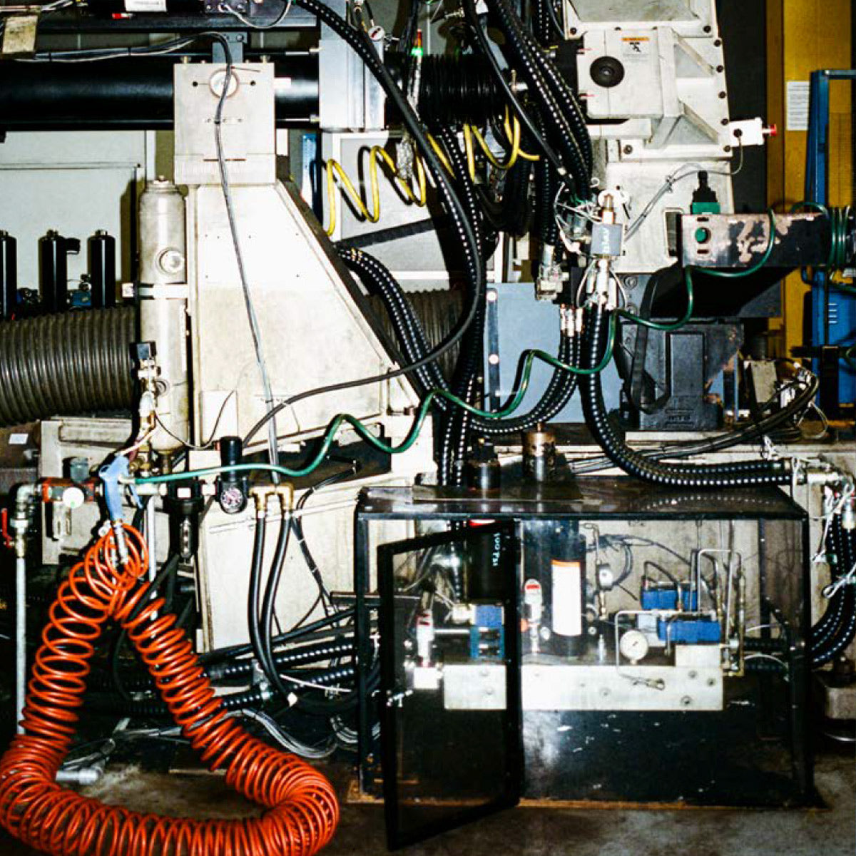 Complex industrial machine with various components and hoses in a workshop setting