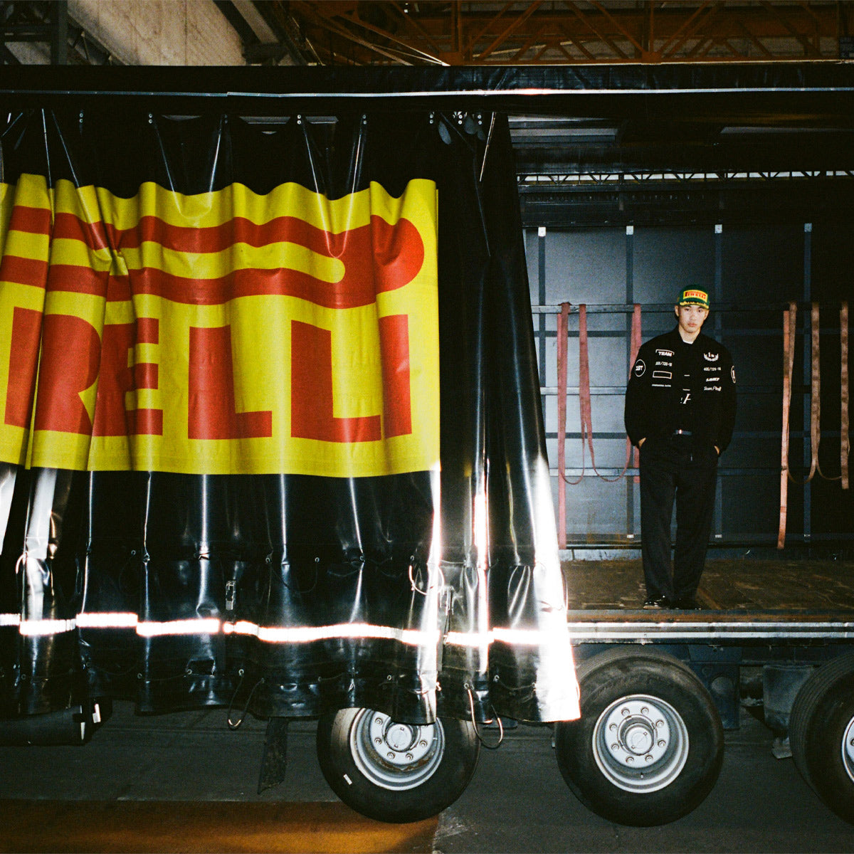 Person standing on a truck bed with a large Pirelli sign in the background