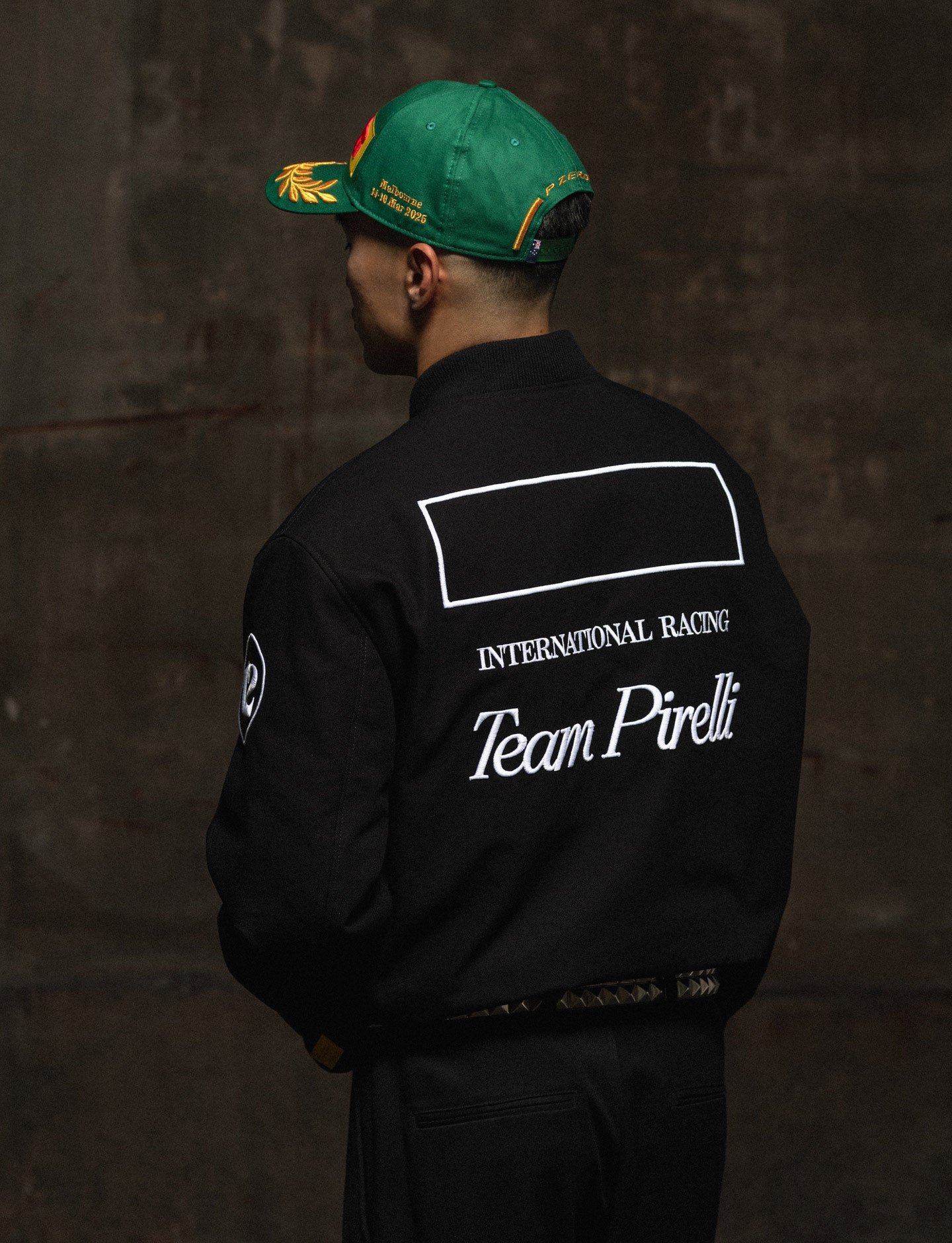 man in Pirelli racing jacket wearing green Pirelli podium cap