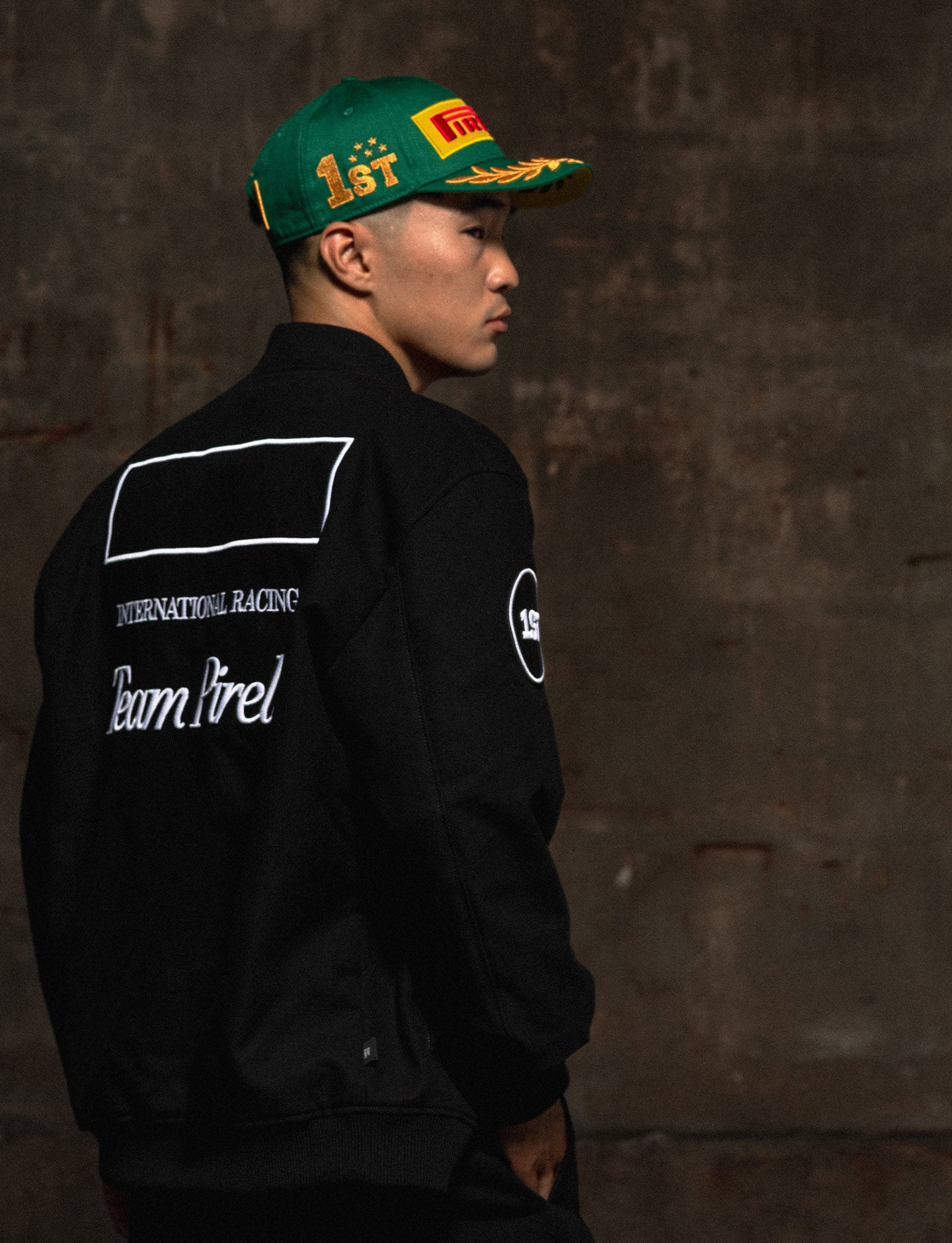 man in Pirelli racing jacket wearing green Pirelli podium cap