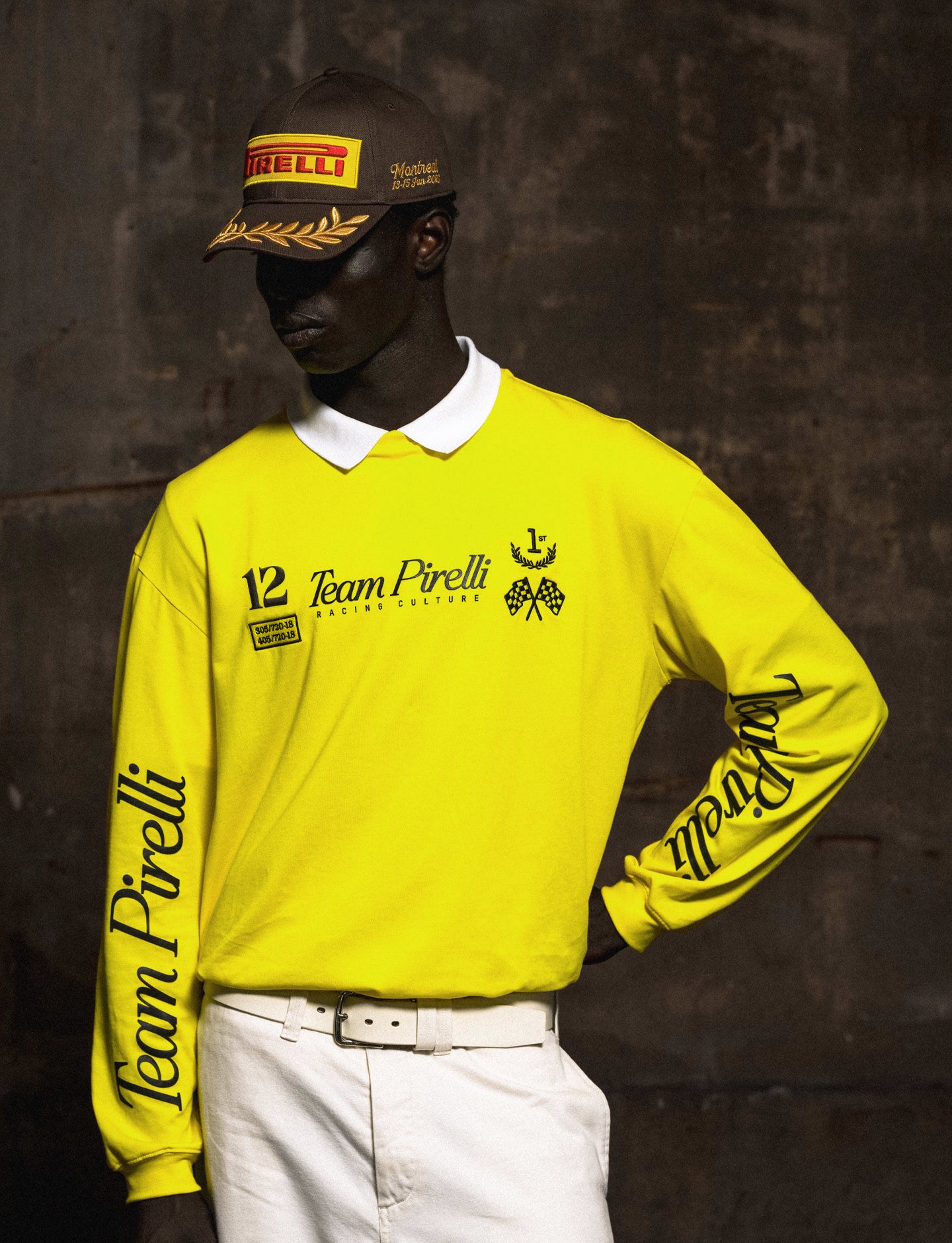 Person wearing a bright yellow 'Team Pirelli' long sleeve tee and Pirelli cap against a dark background