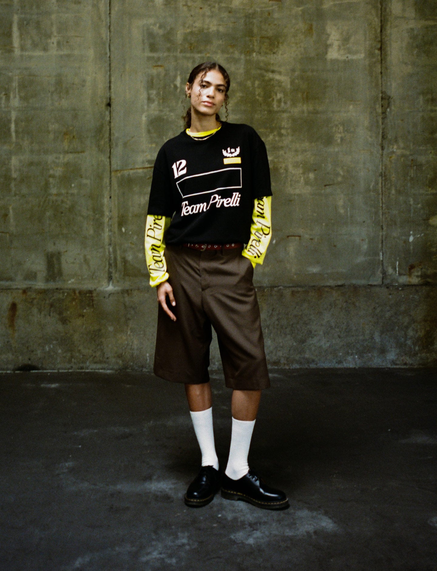 Person wearing a black and yellow Pirelli outfit with visible branding against a textured wall.