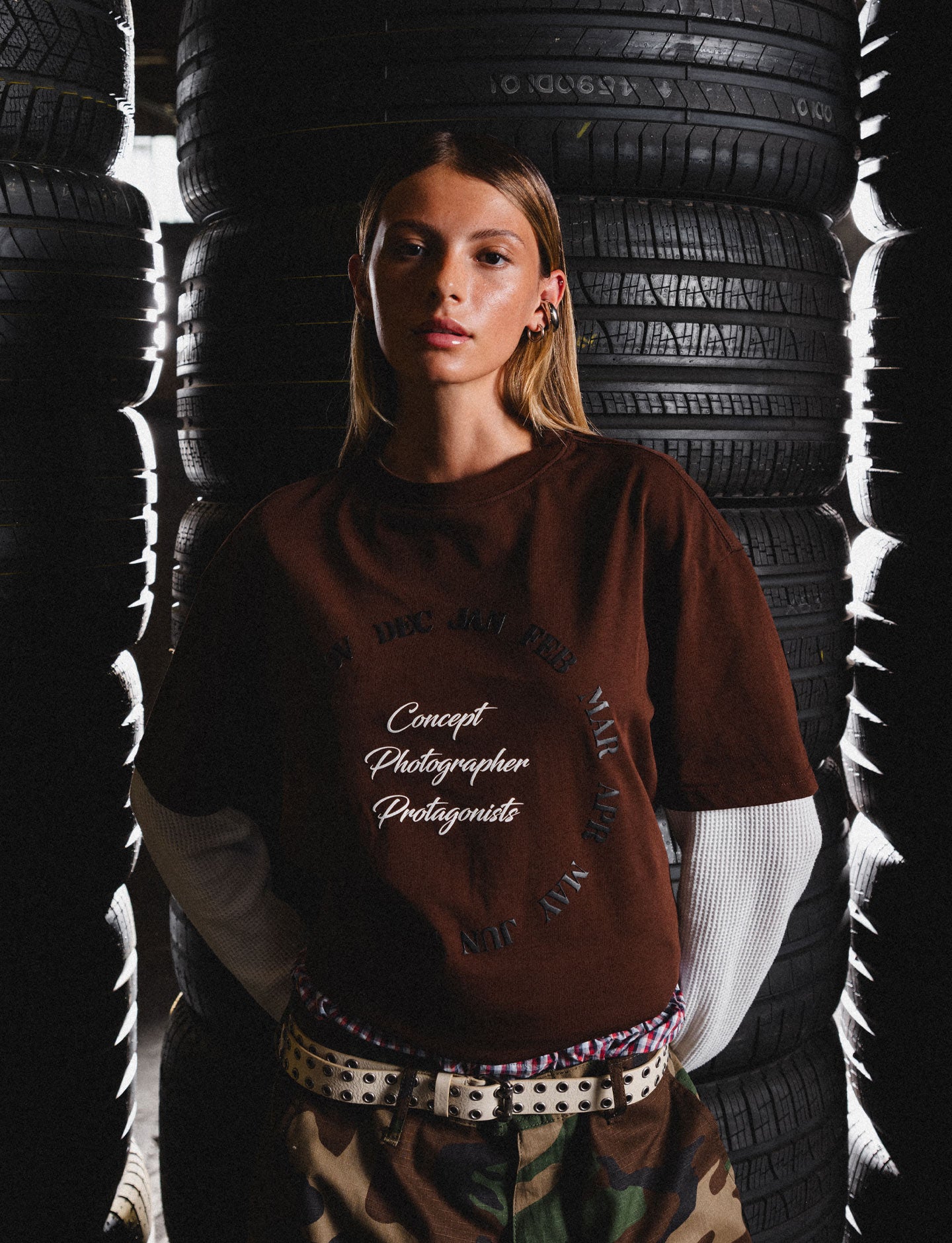 Person wearing a brown Pirelli graphic t-shirt in a tire-filled environment