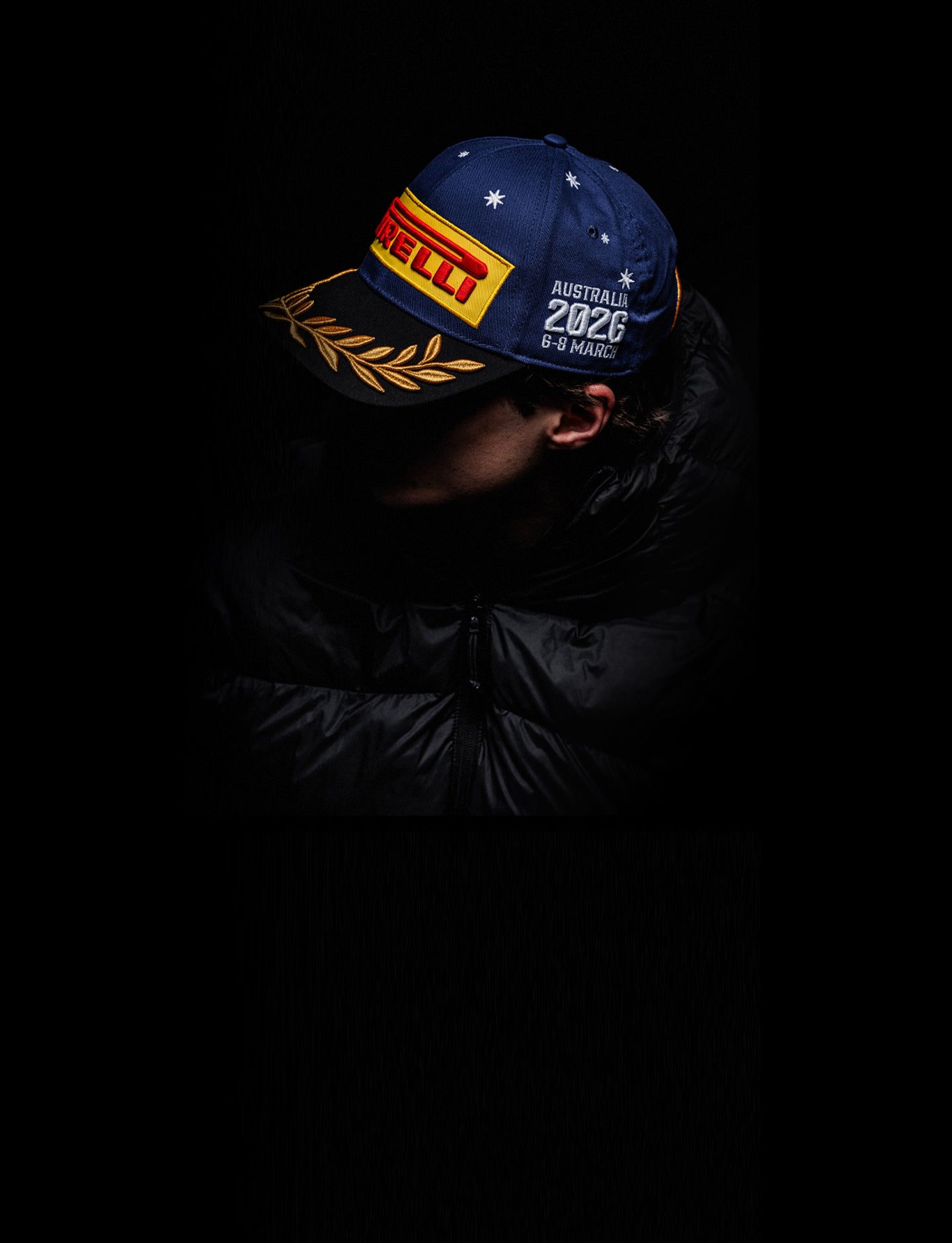 man wearing a Pirelli Australia Podium Cap 2026 against a dark background