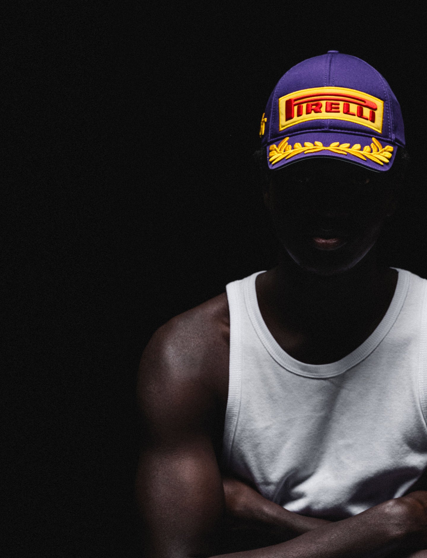 Person wearing a purple Pirelli branded F1® cap on a black background
