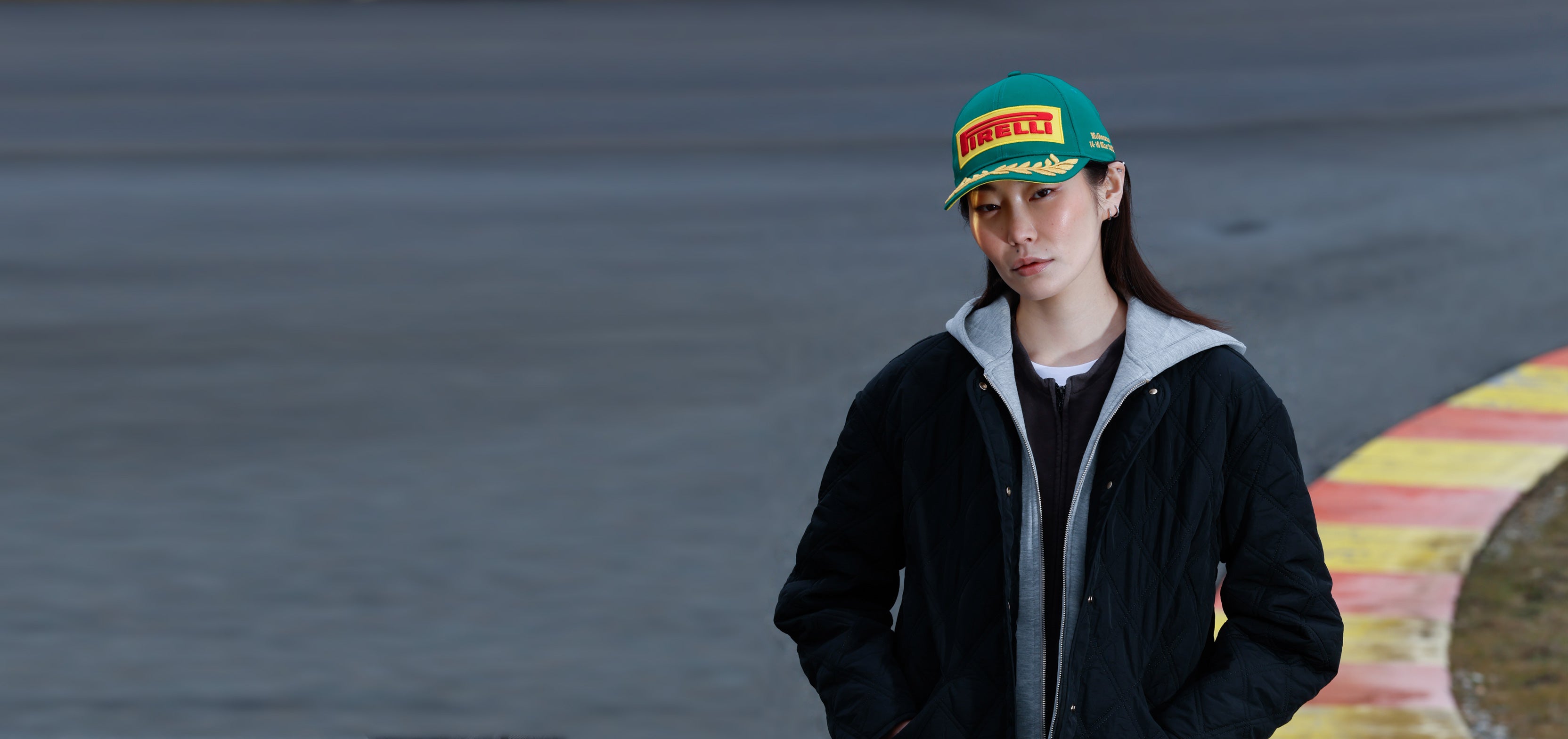 woman in green Pirelli Podium Cap at racetrack