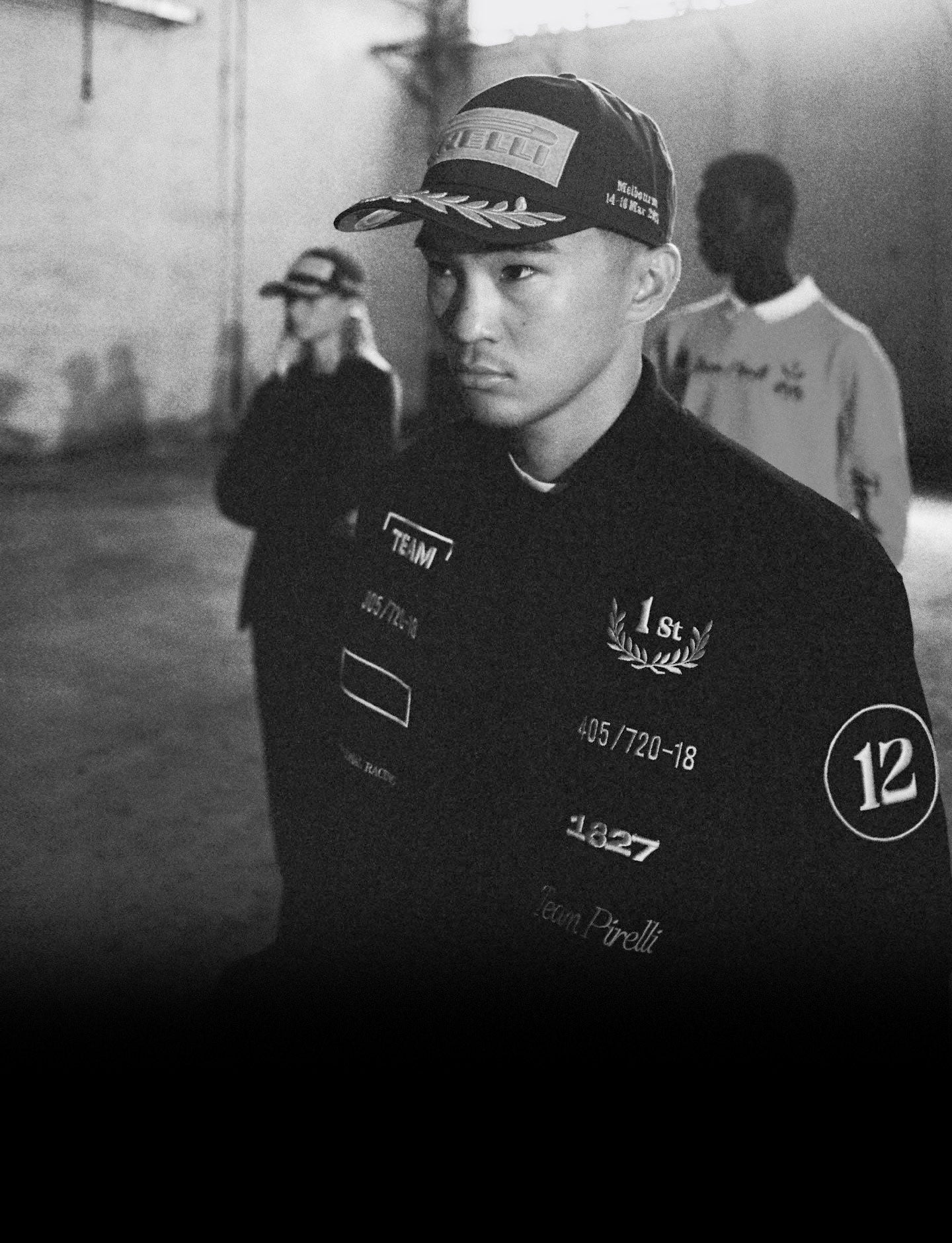 black and white photo of three people wearing Pirelli clothing and caps in a warehouse setting