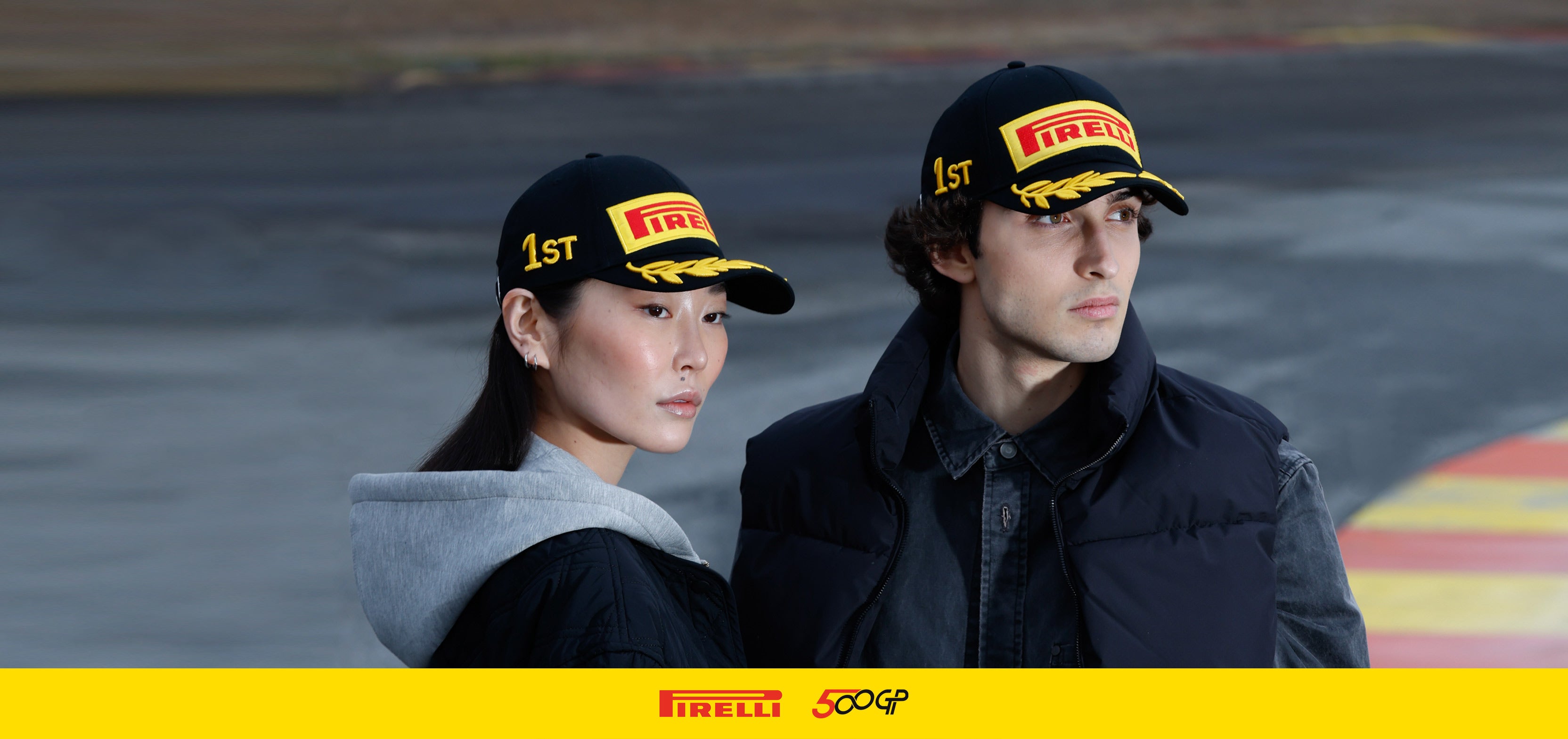 Two people wearing Pirelli hats on a race track
