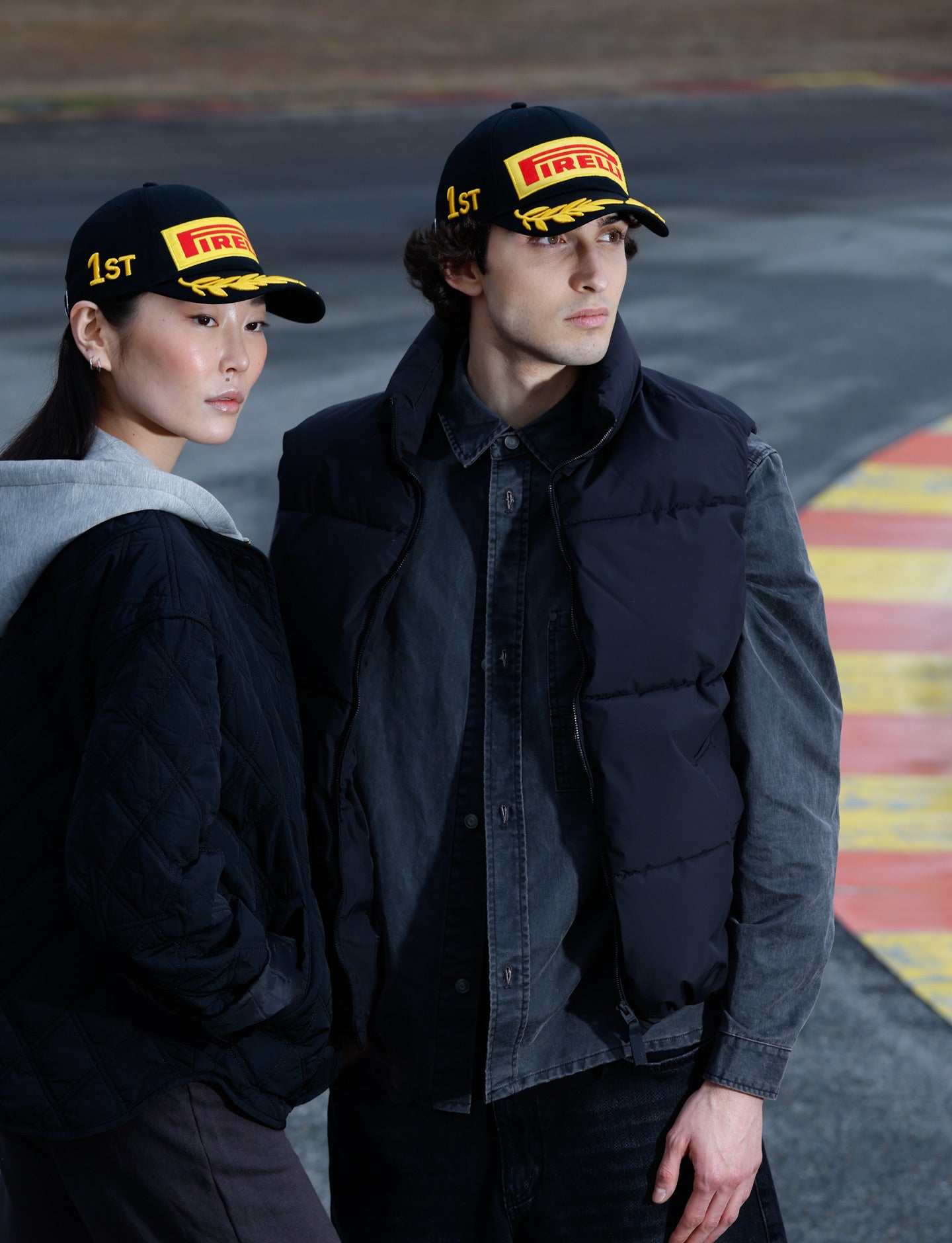 Two people wearing Pirelli hats on a F1 racetrack