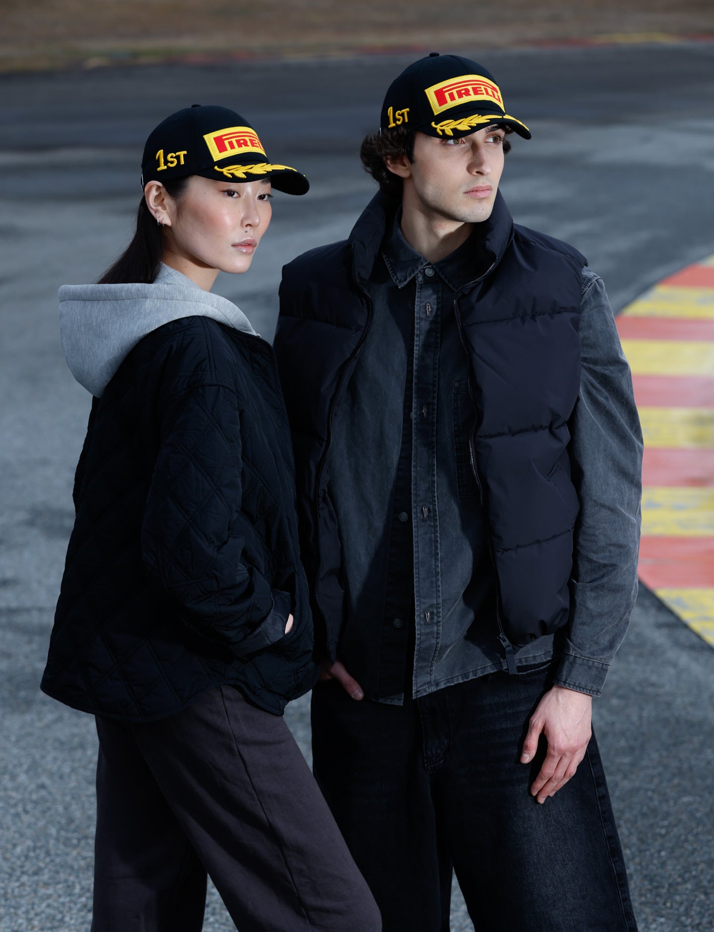 Two people wearing Pirelli hats on a racetrack