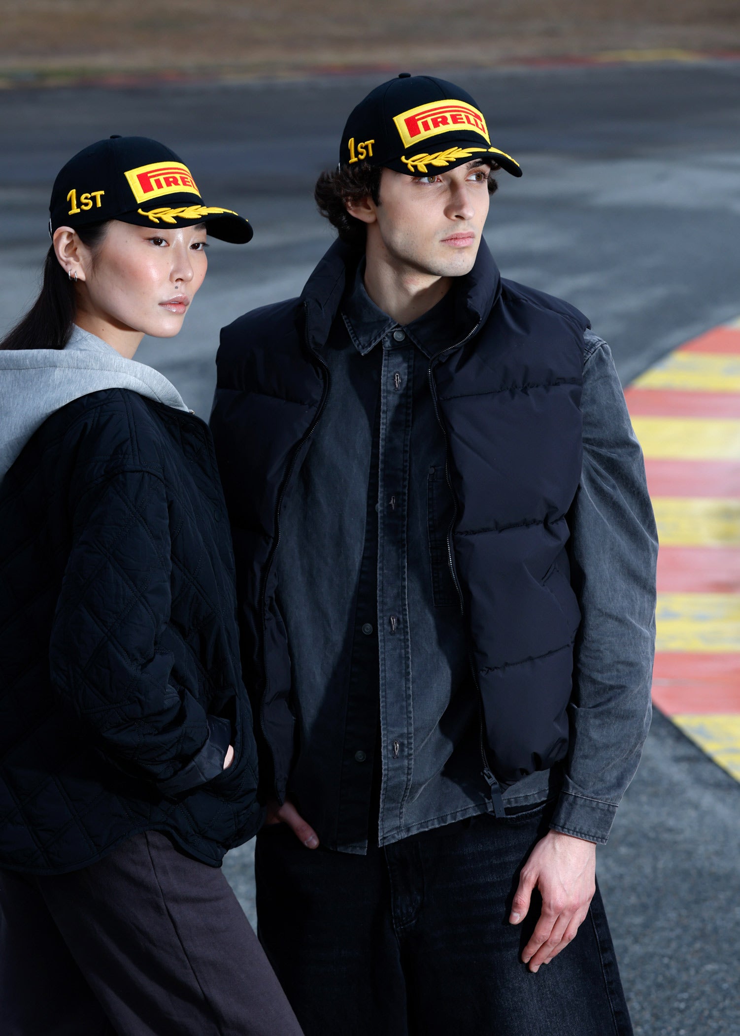 man and woman in black Pirelli podium cap at racetrack