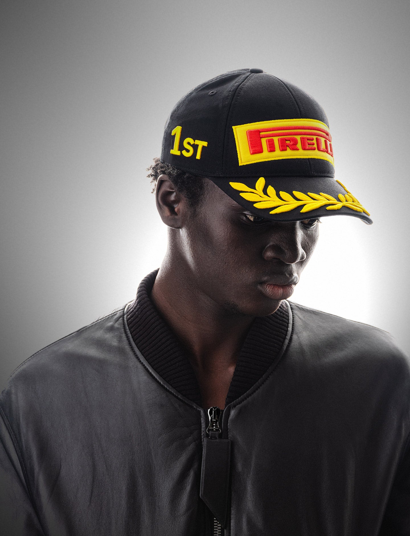 Person wearing a black cap with Pirelli logo and '1ST' text on a gray background