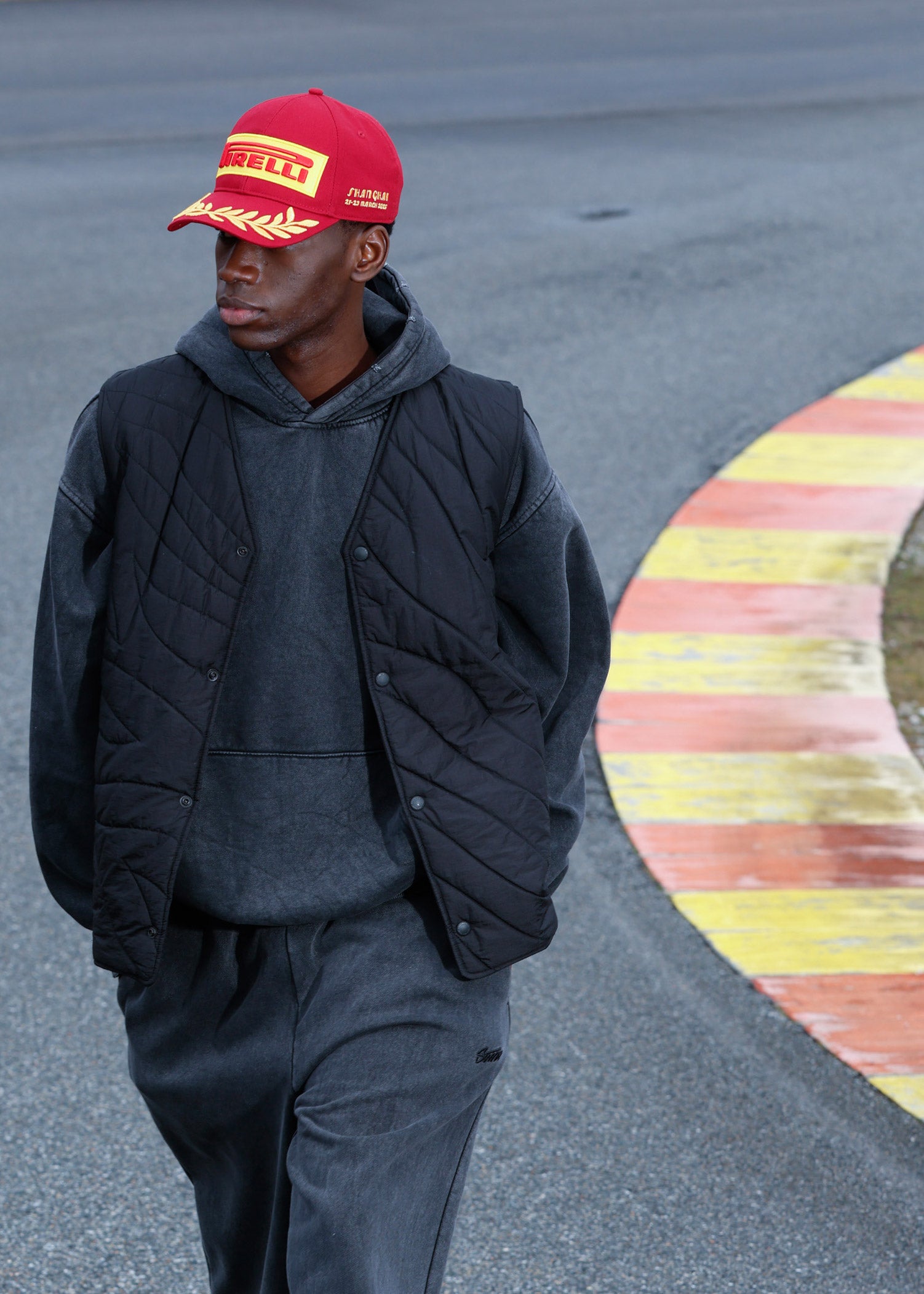 man in red Pirelli Podium Cap on racetrack