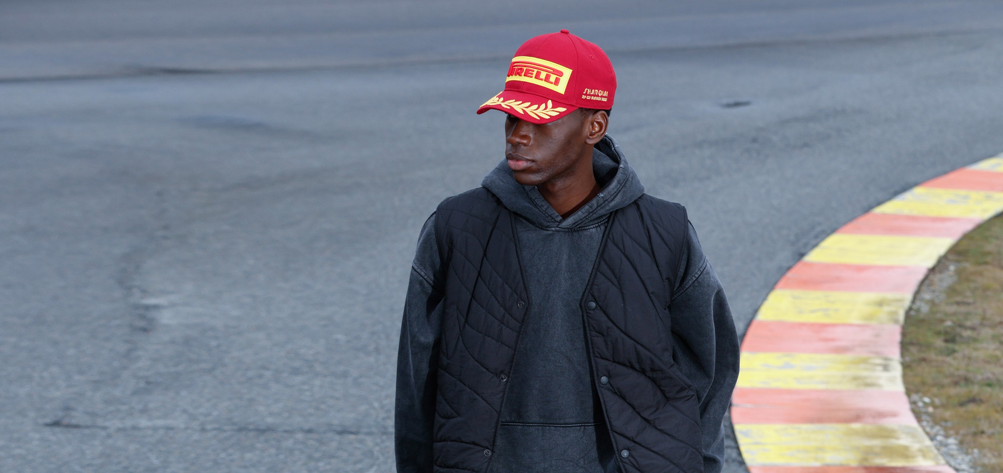 man in red Pirelli Podium Cap at racetrack