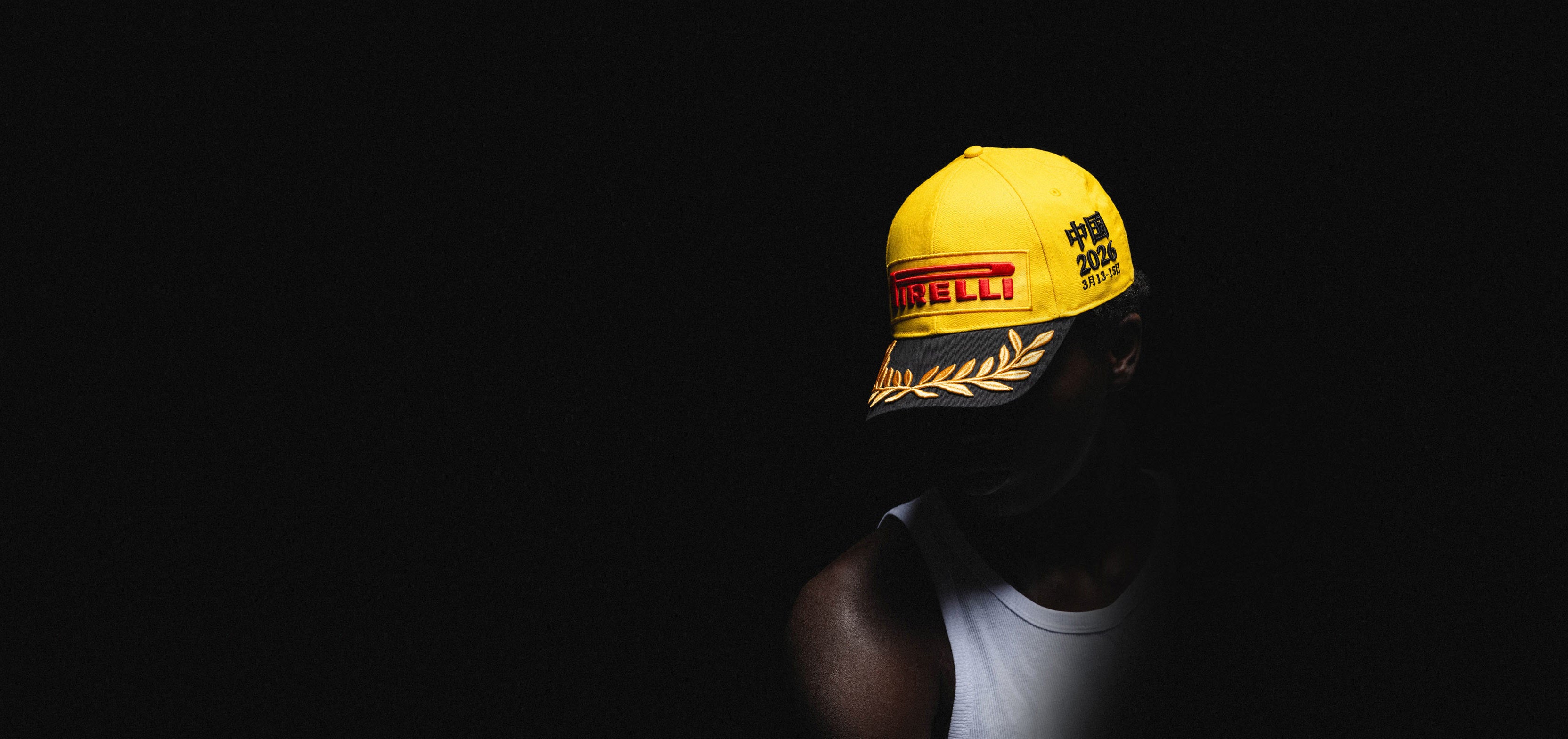 Person wearing a yellow and black Pirelli Podium Cap on a black background