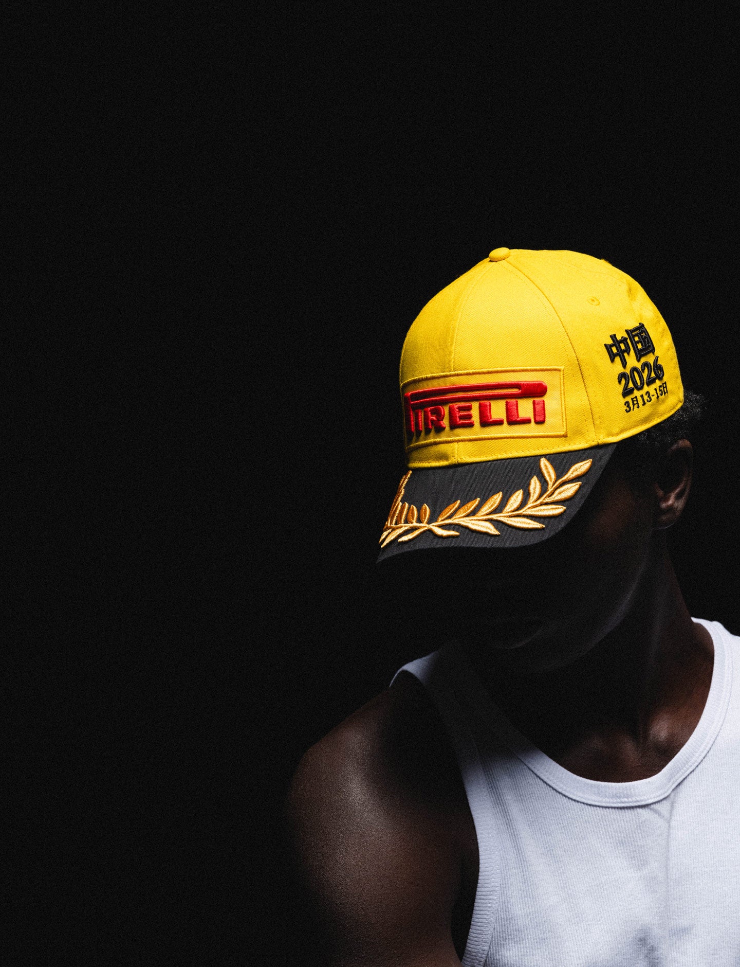 Person wearing a yellow and black Pirelli Podium Cap on a black background
