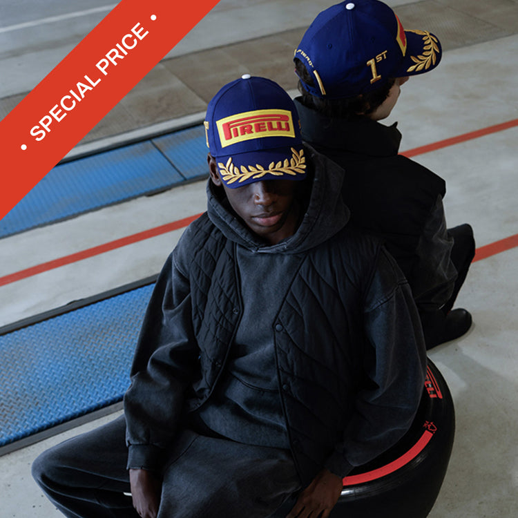 Two people wearing hats with Pirelli logo sitting on a tyre.