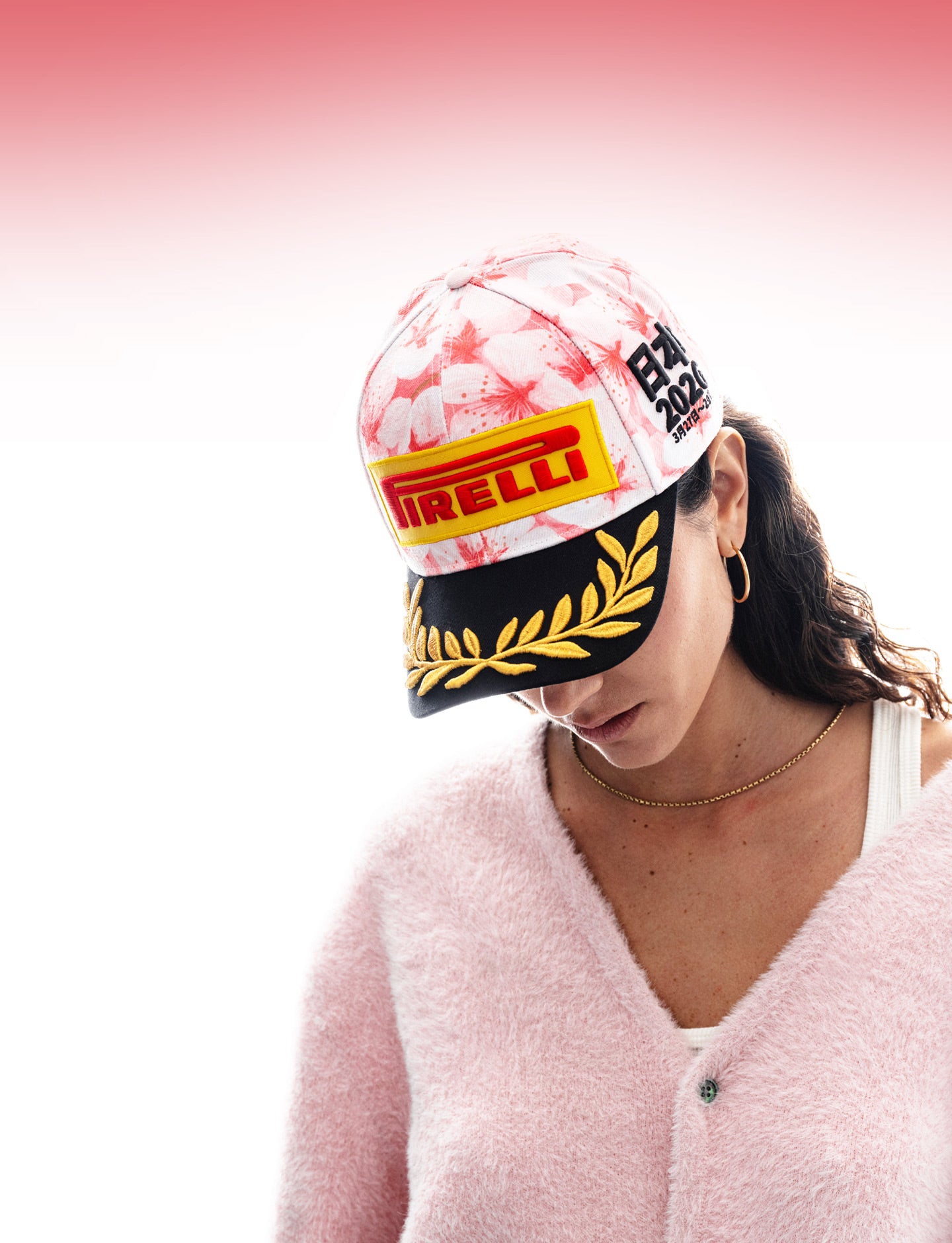 Person wearing a cherry blossom pattern cap with Pirelli logo on a white background