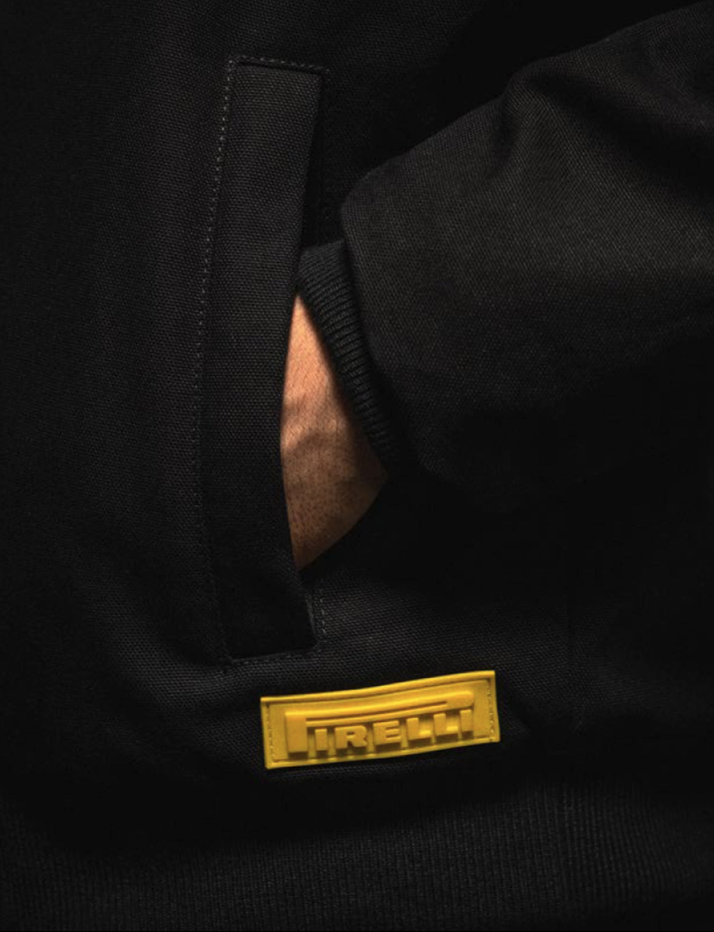 Black jacket close-up with a 3D Pirelli logo on a dark background