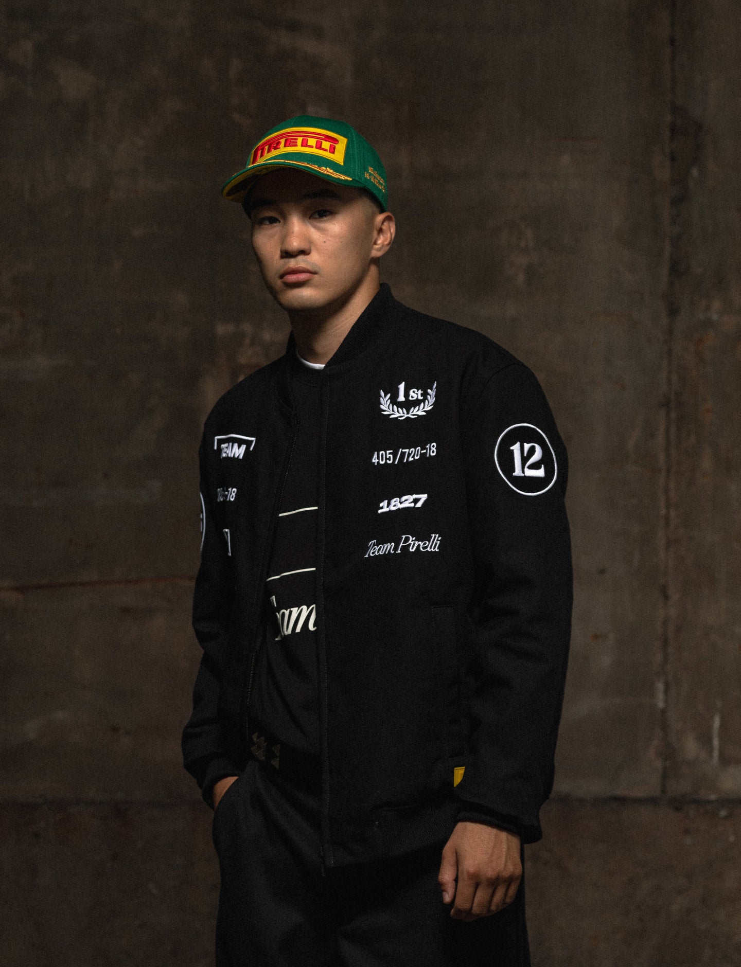 Person wearing a black Pirelli racing jacket against a dark background