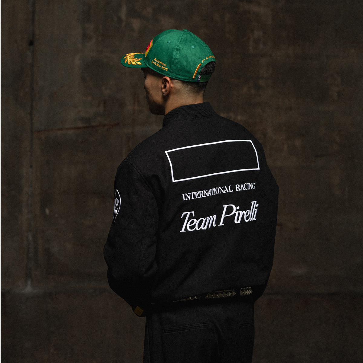 Person wearing a black jacket with 'Team Pirelli' branding against a dark background