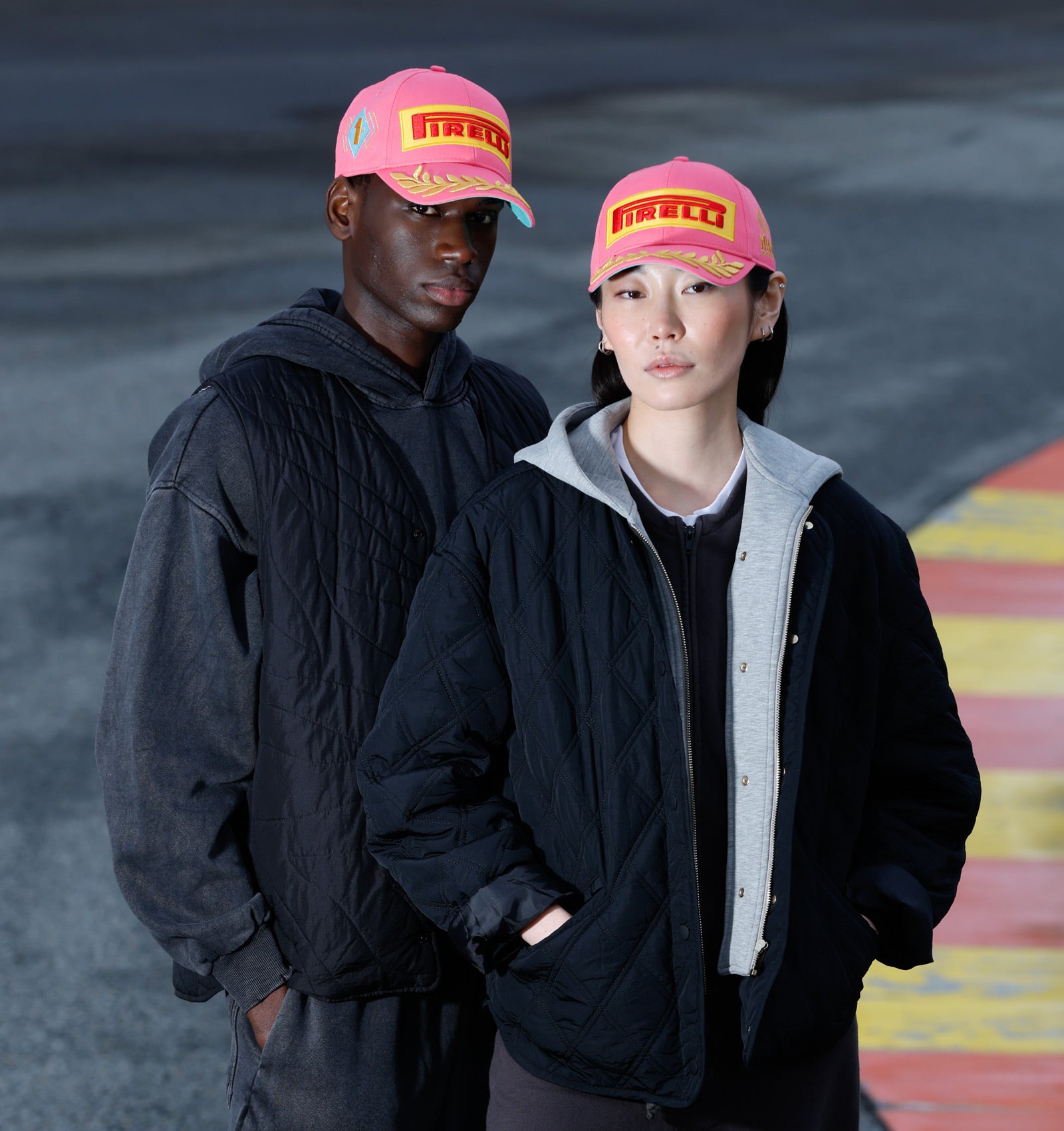 man and woman in pink Pirelli Podium Cap at racetrack