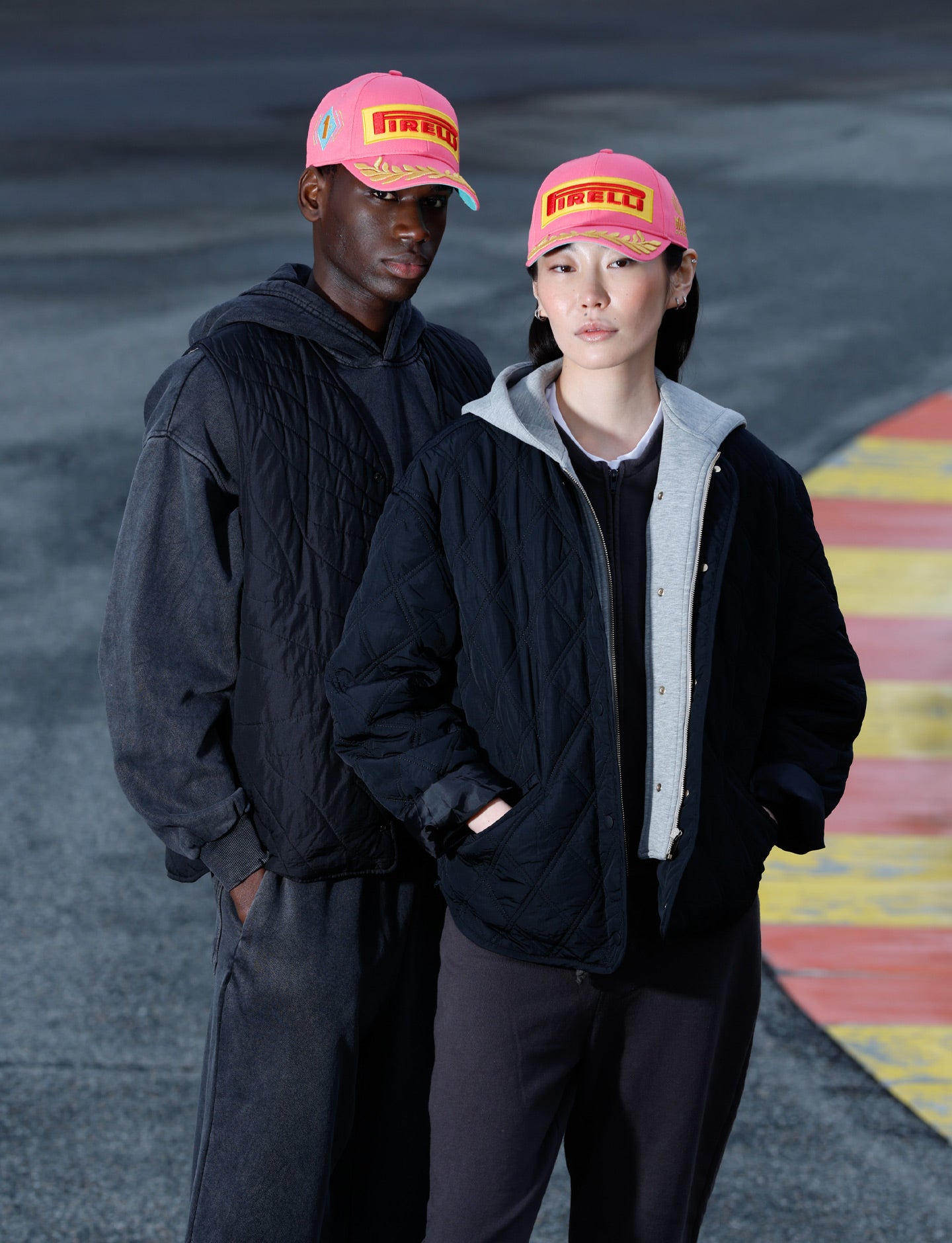 two people at racetrack wearing pink Pirelli podium caps