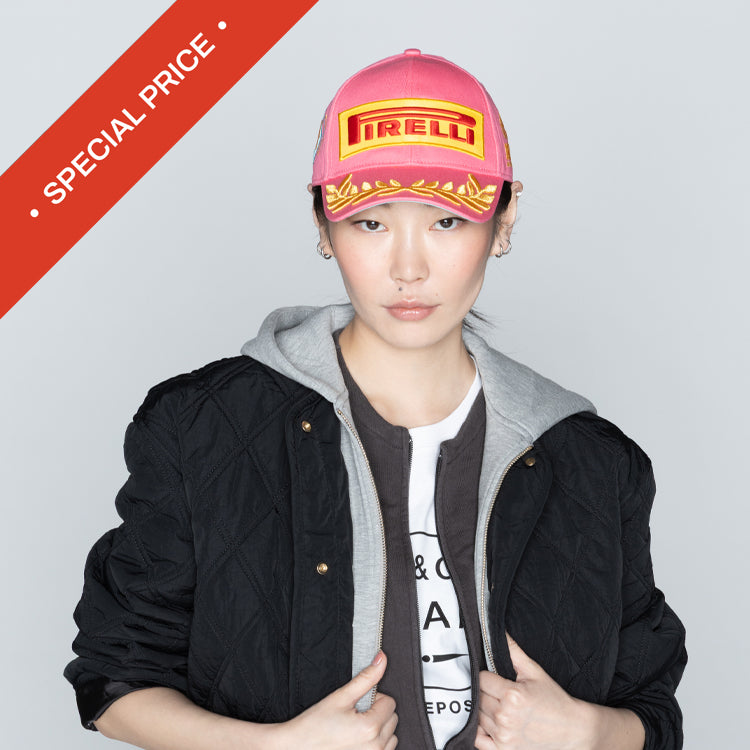 Person wearing a pink cap with a Pirelli logo on a gray background