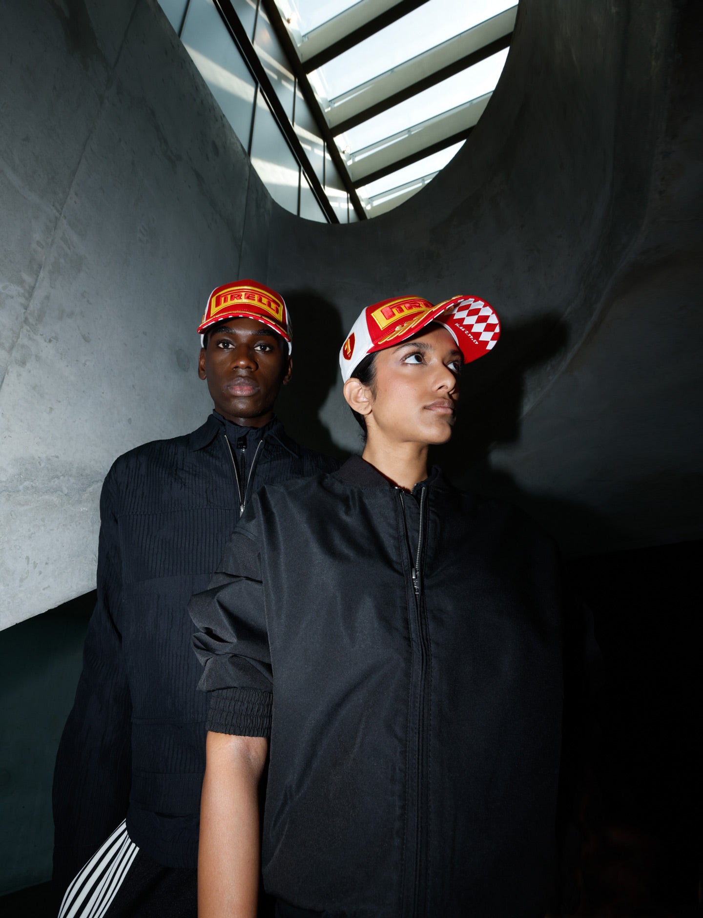 Two people wearing Pirelli hats in a dark indoor setting.