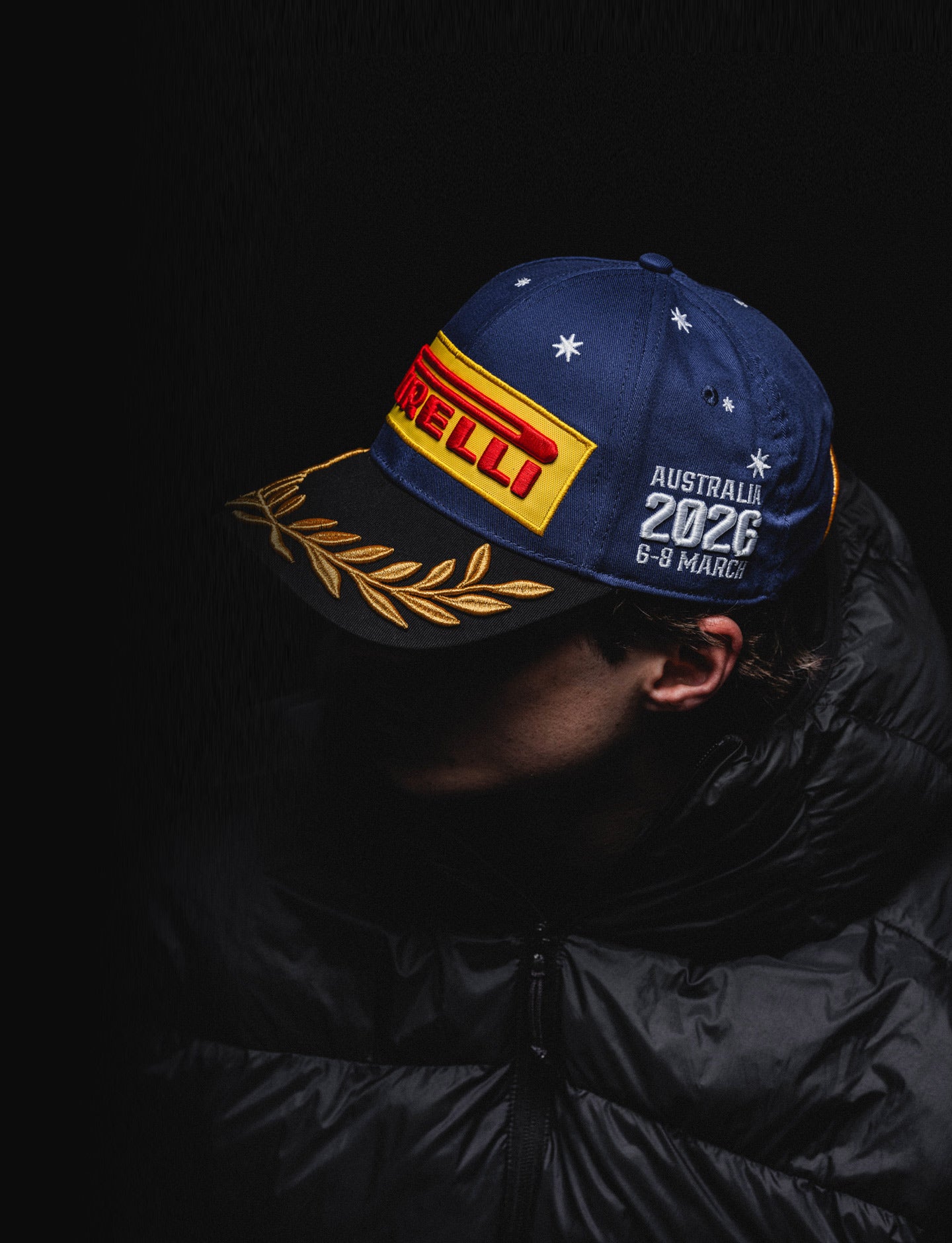 Person wearing a blue cap with Pirelli logo and 'Australia 2026' text on a dark background