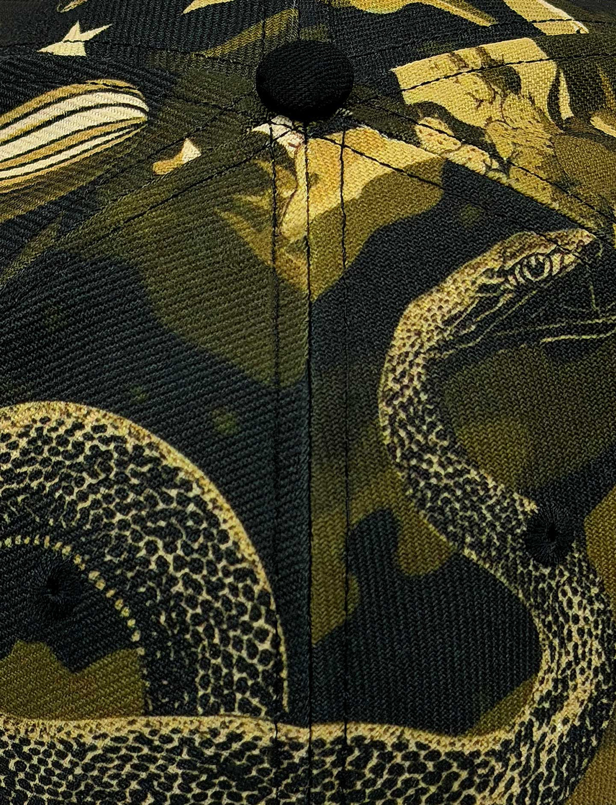 Close-up of a fabric surface with a printed snake and abstract camouflage-like pattern in olive green, black, tan, and cream tones.