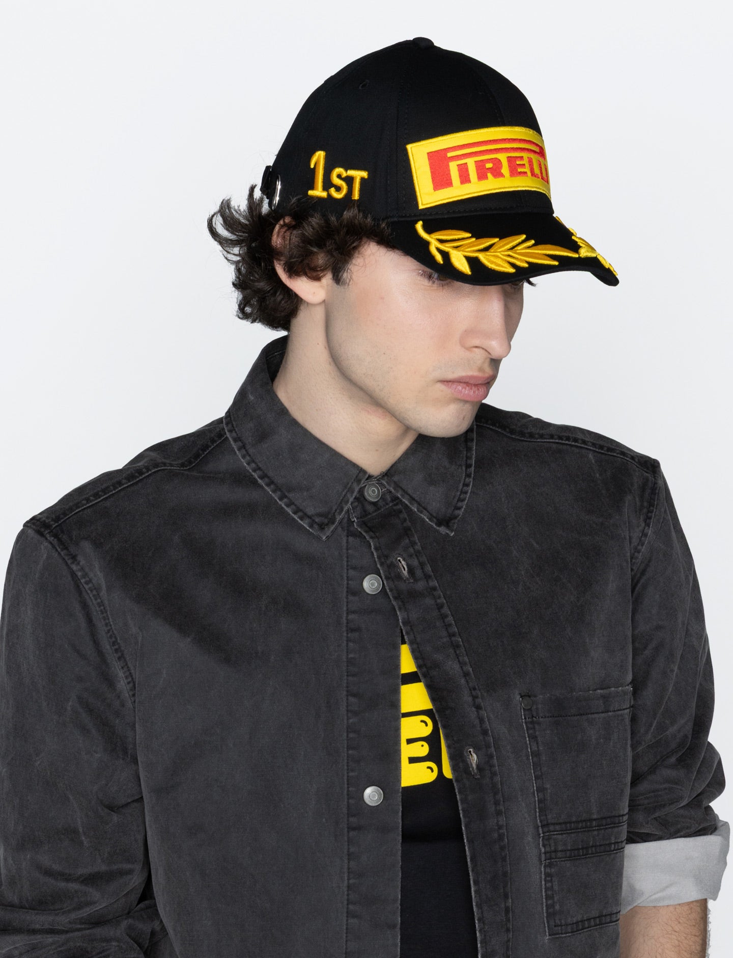 Person wearing a black cap with Pirelli logo and yellow text on a white background