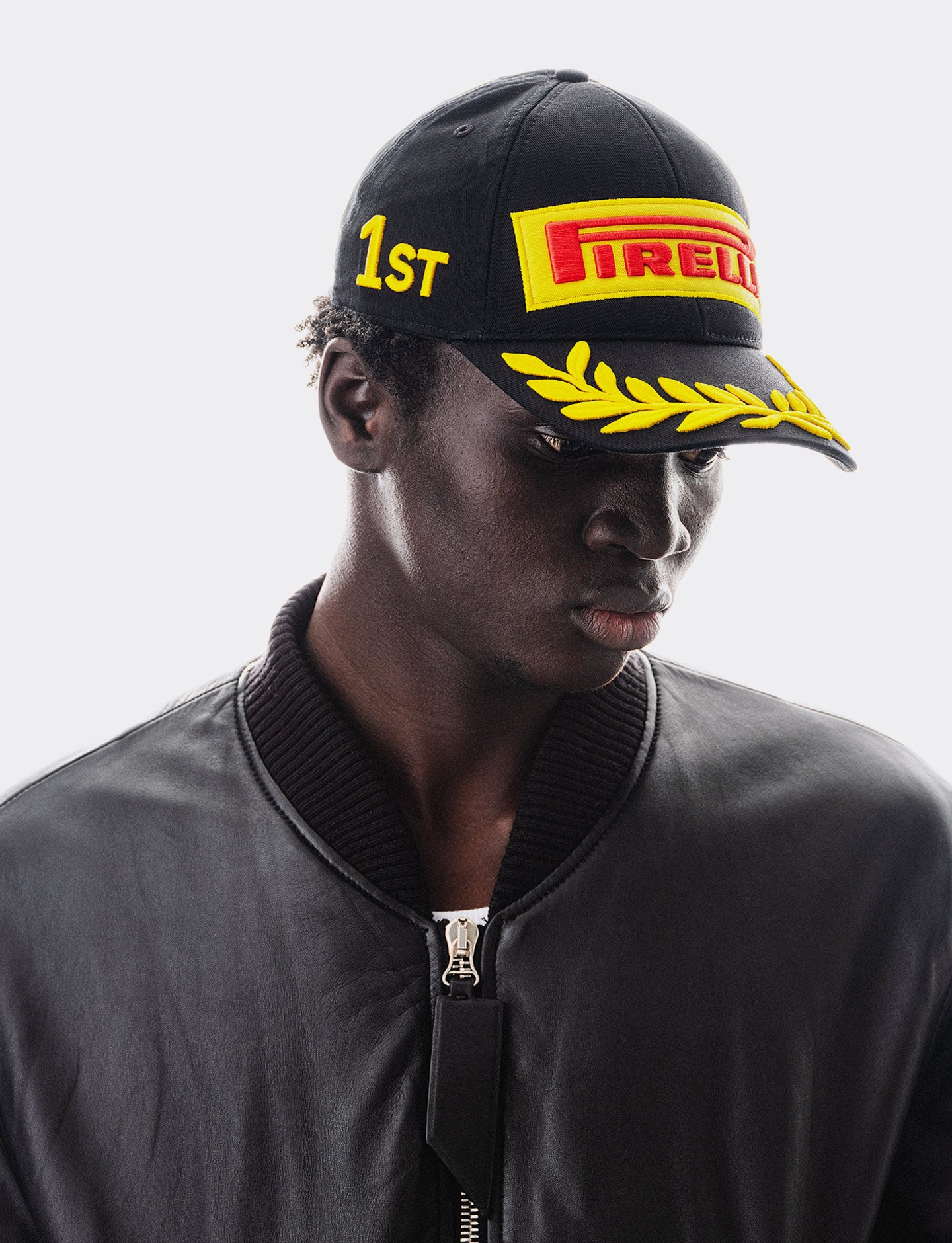 Person wearing a black cap with Pirelli logo and '1ST' text on a white background