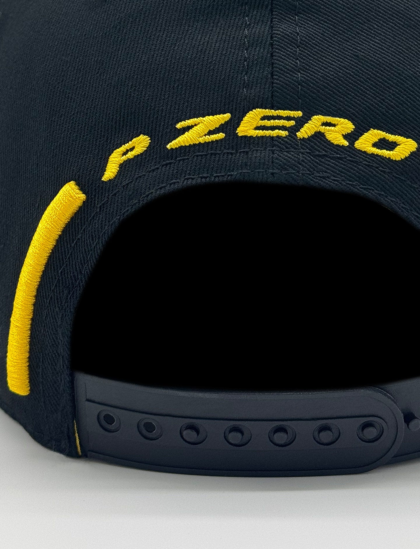 Black Pirelli cap with yellow 'P Zero' embroidery on a light gray background