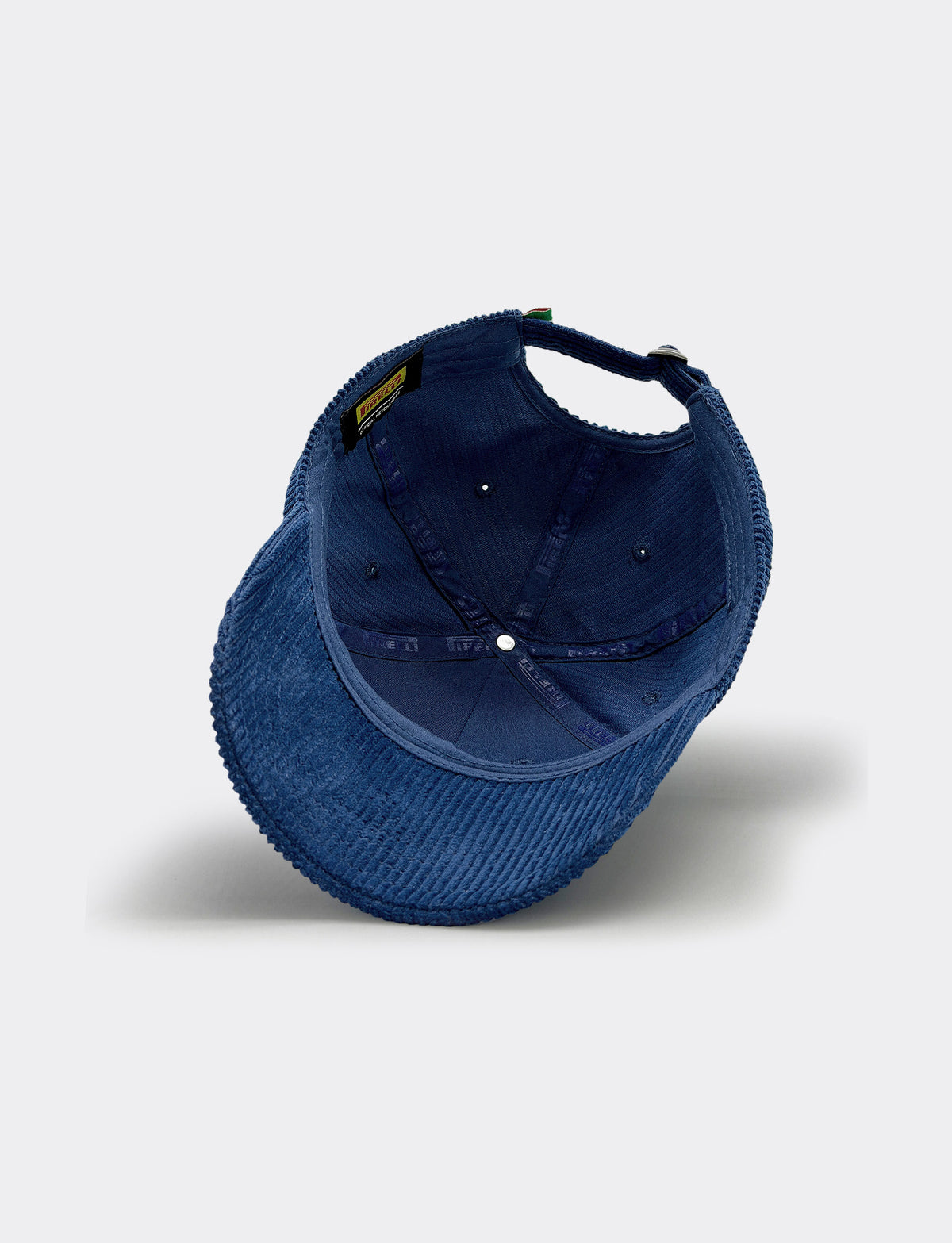 A dark blue Pirelli corduroy baseball cap shown from an angled top-down view on a light gray background.