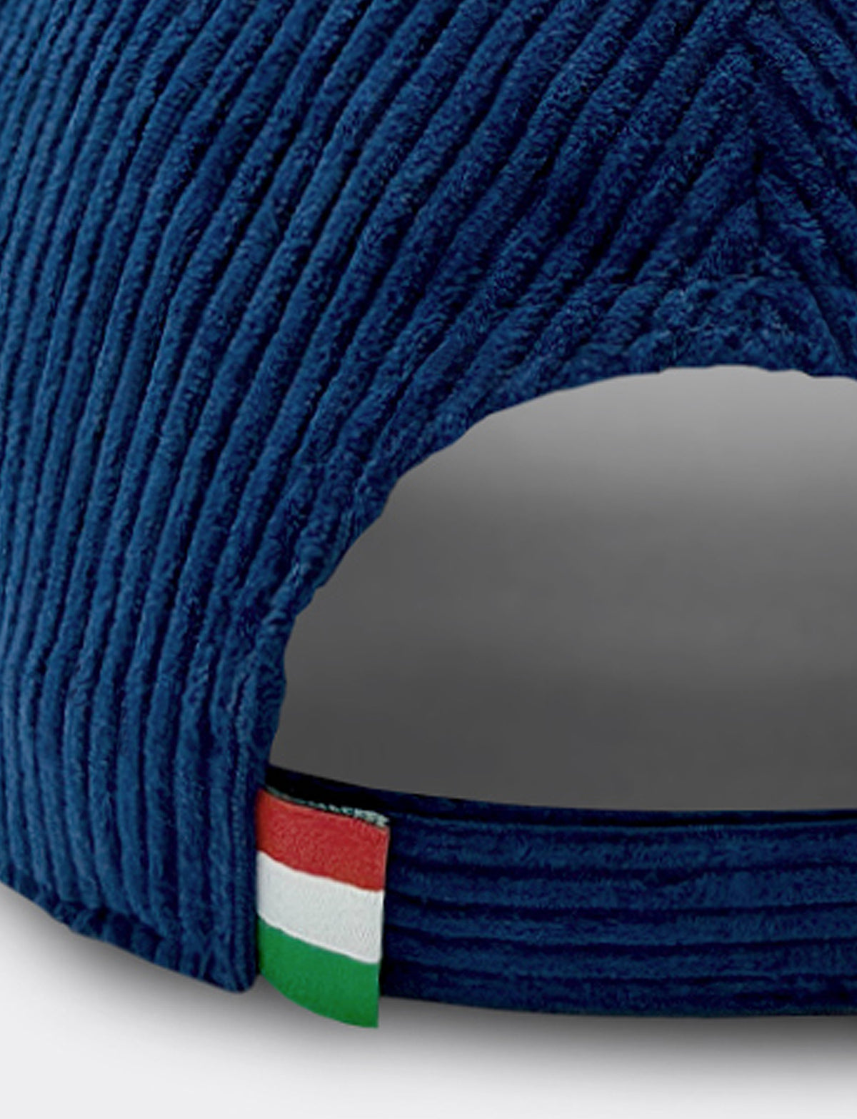 Close-up of a dark blue Pirelli corduroy cap with a small Italian flag patch on the back band.
