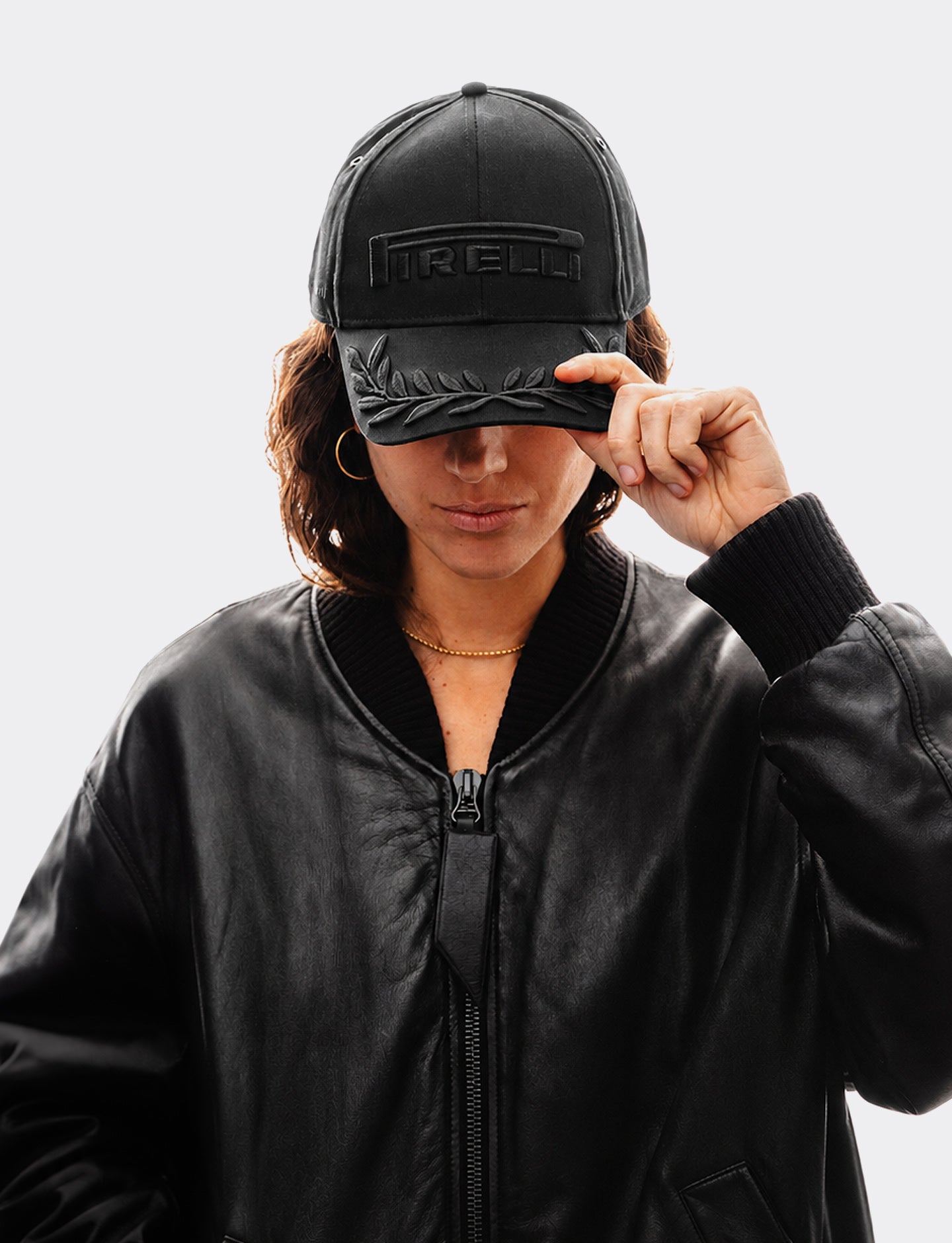 Woman wearing a black tonal Pirelli cap on a light gray background