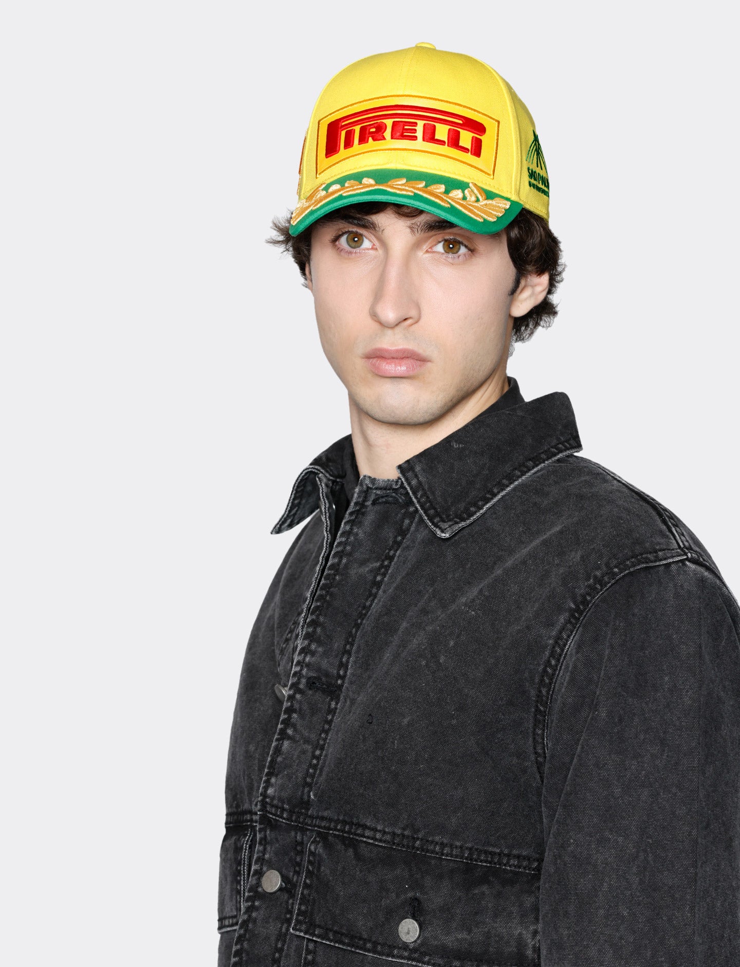 Person wearing a yellow Pirelli cap on a white background