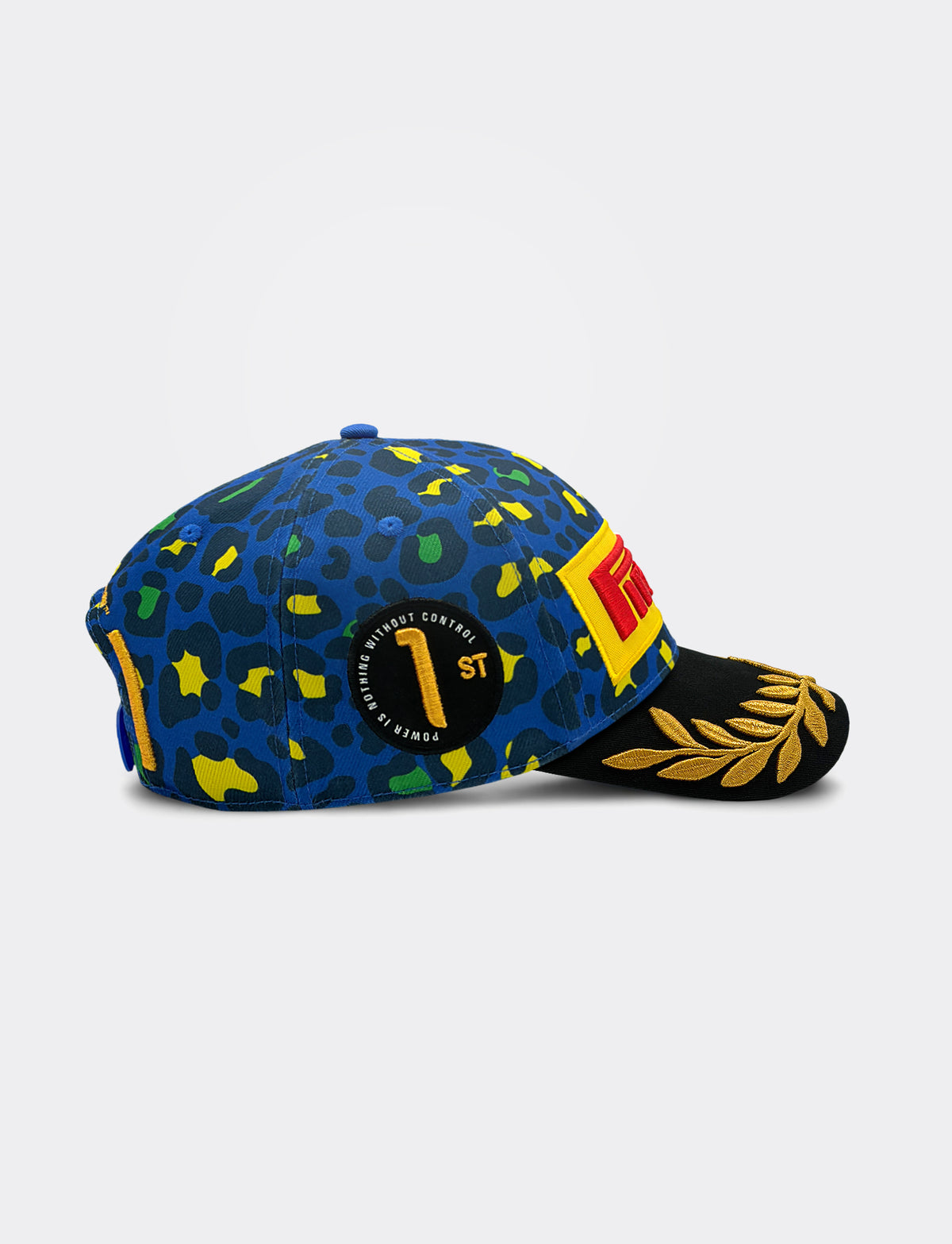 A right-facing blue Pirelli baseball cap with a jaguar print pattern in yellow, green, and black, featuring yellow embroidered text that reads '1st' and 'POWER IS NOTHING WITHOUT CONTROL. The brim is black with a gold laurel leaf design, and a red and yellow Pirelli logo patch is visible on the front side.