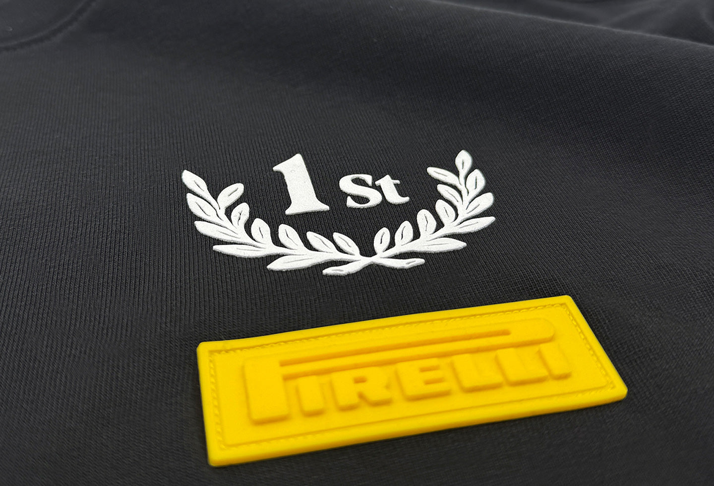 Black fabric with '1st' and laurel wreath design, yellow Pirelli brand logo below.