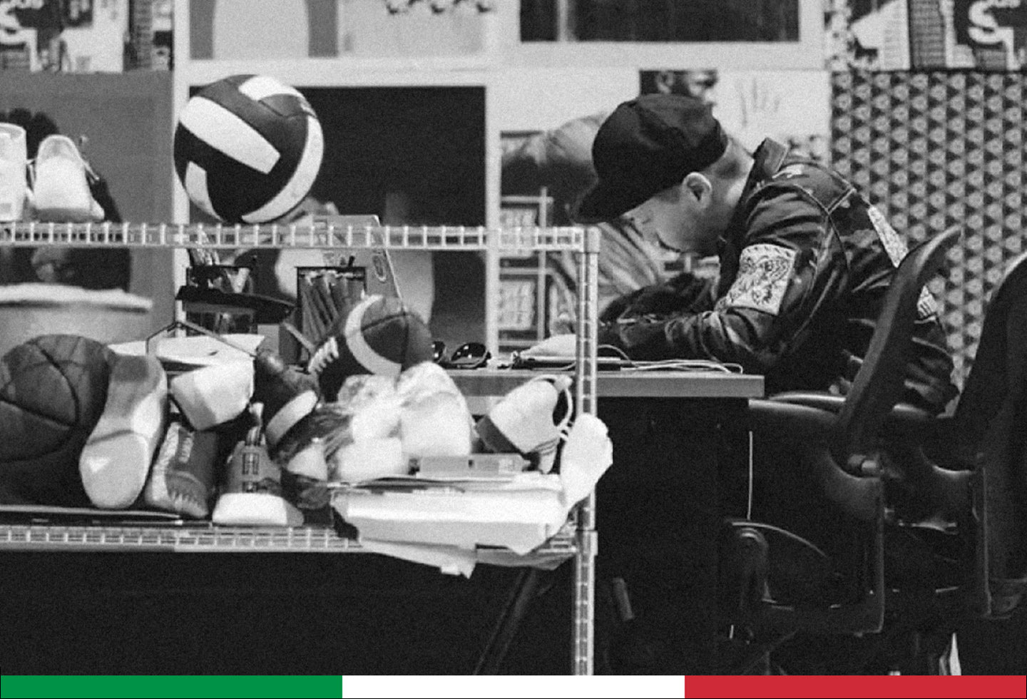 Person sitting at a desk with sports balls and equipment in the background
