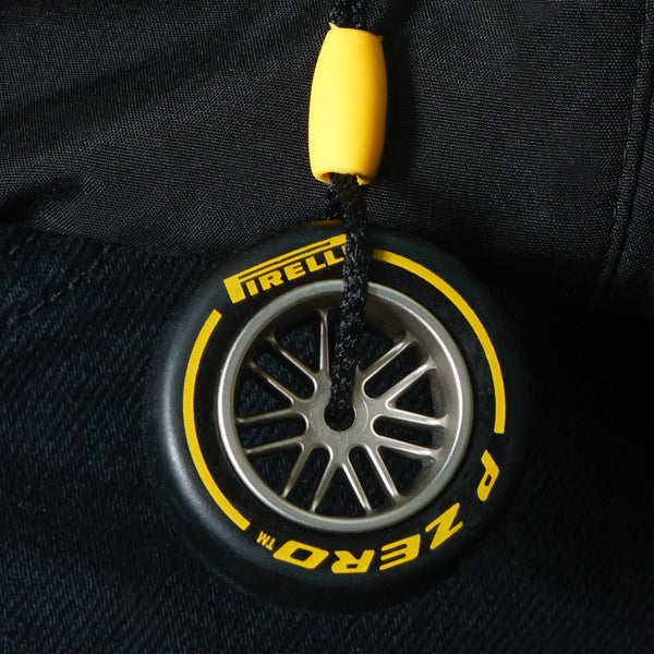 Pirelli tire-shaped keychain with yellow accents on a black background