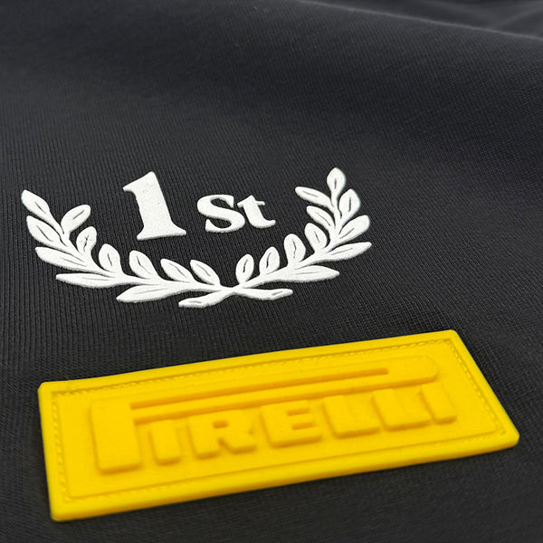 Black t-shirt with '1st' and laurel wreath design, yellow patch with 'Pirelli' branding.