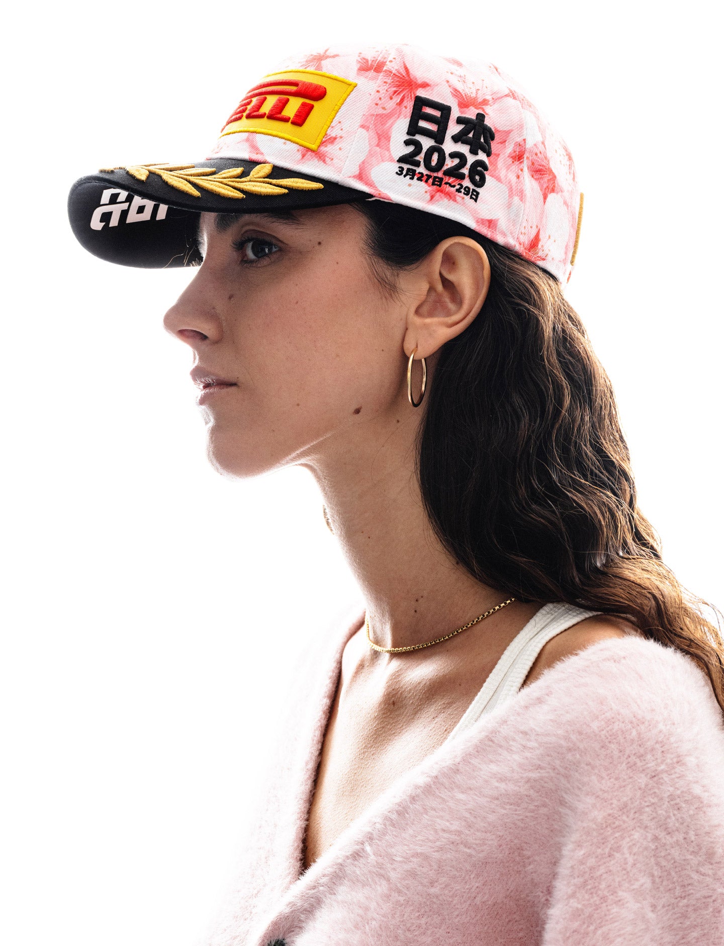 Person wearing a pink and black cap with Pirelli logo on a white background